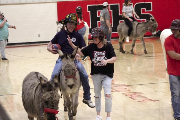 Earlsboro teacher Lisa Coomer tries to steal the ball from fire fighter Cal Locke, while off her donkey, during the Donkey Basketball game at Earlsboro High School on April 9. The Town of Earlsboro fund-raiser featured two games: Earlsboro Police and Fire Departments vs. Earlsboro Teachers and the Mize Agency vs. Earlsboro students. They also raised money through a dessert drawing, silent auction and a pre-game dinner.