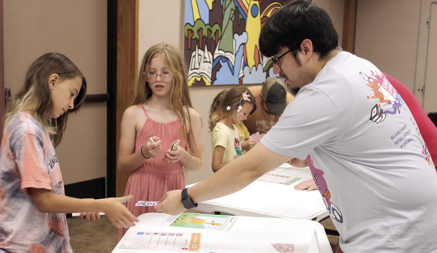 Shawnee Public Library Children's Librarian Jairo Montelongo gives change to Hadley Blake, 10, of Bethel, during the 'Pet Cents' event on June 14. Using play money, Blake bought an ostrich for her pet, and Brylynn Pointer, 11, of Shawnee, bought a giraffe. Montelongo said the library received an American Library Association grant to teach children how to manage finances. Their next event, Making Moo-La, will be on June 21 at 10:30 am. 