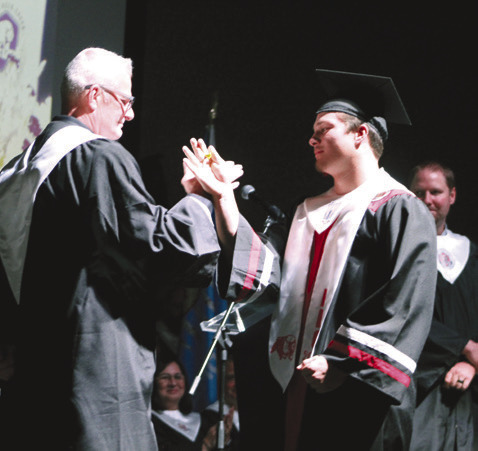 North Rock Creek High School Principal Chad Brooking shares a secret handshake with his son Holden Brooking after the graduate received his diploma at graduation on May 19. Countywide &amp; Sun/ Natasha Dunagan