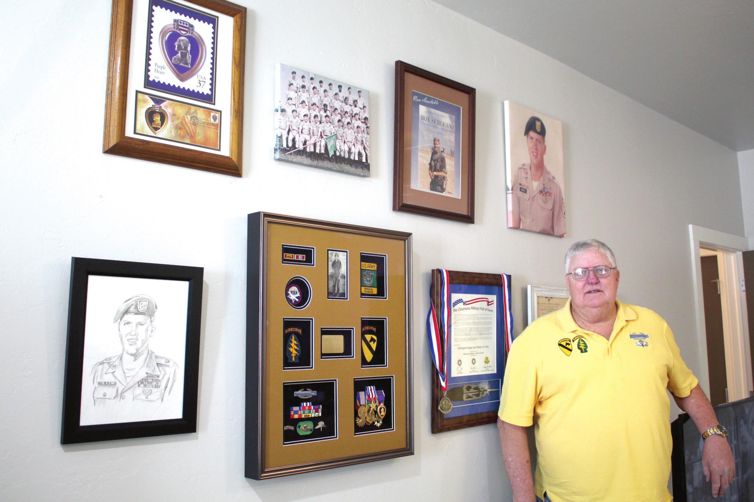 SSG Douglas Warden, of Shawnee, stands by a wall of military mementos, photos, and medals. Warden was inducted into the Oklahoma Military Hall of Fame in October. Countywide &amp; Sun/Natasha Dunagan