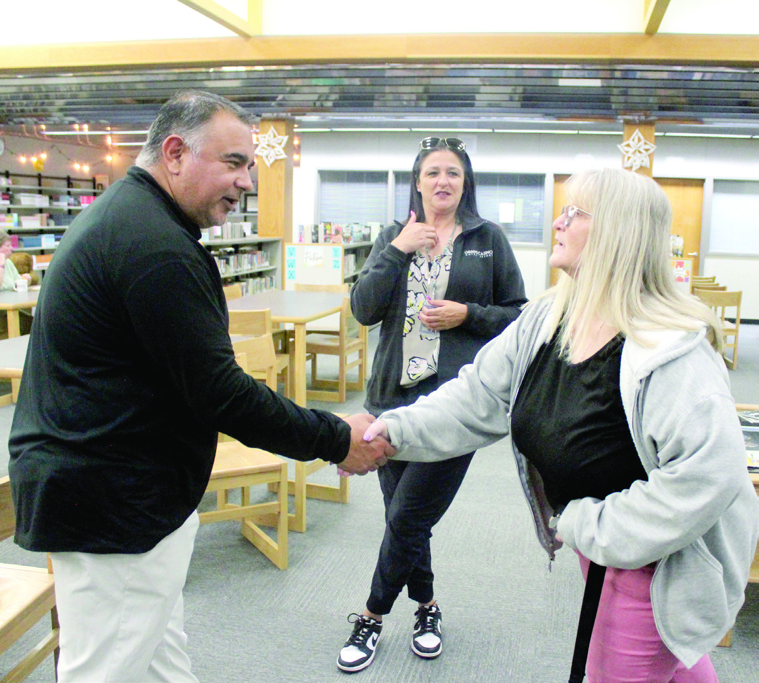 New Tecumseh High School Head Football Coach Randon Lowe shakes hands with English teacher Valerie Stokes, as parent Tedda Hogan looks on, during the meet-and-greet held in the THS library on April 21. Mike Montano, the new Defensive Coordinator, was also at the event. Natasha Dunagan, Countywide &amp; Sun