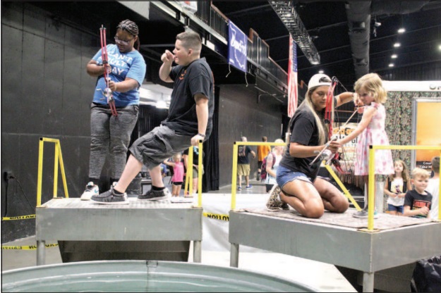 Jadelyn Greer, 15, of Shawnee, and Quinn Jones, 3, of Yukon, get help target bowfishing from Zak McMunn and Jaci Statton, respectively, from Darkwater Adventures of Meeker during the Outdoor Nation Expo on Aug. 13. Countywide & Sun/Natasha Dunagan
