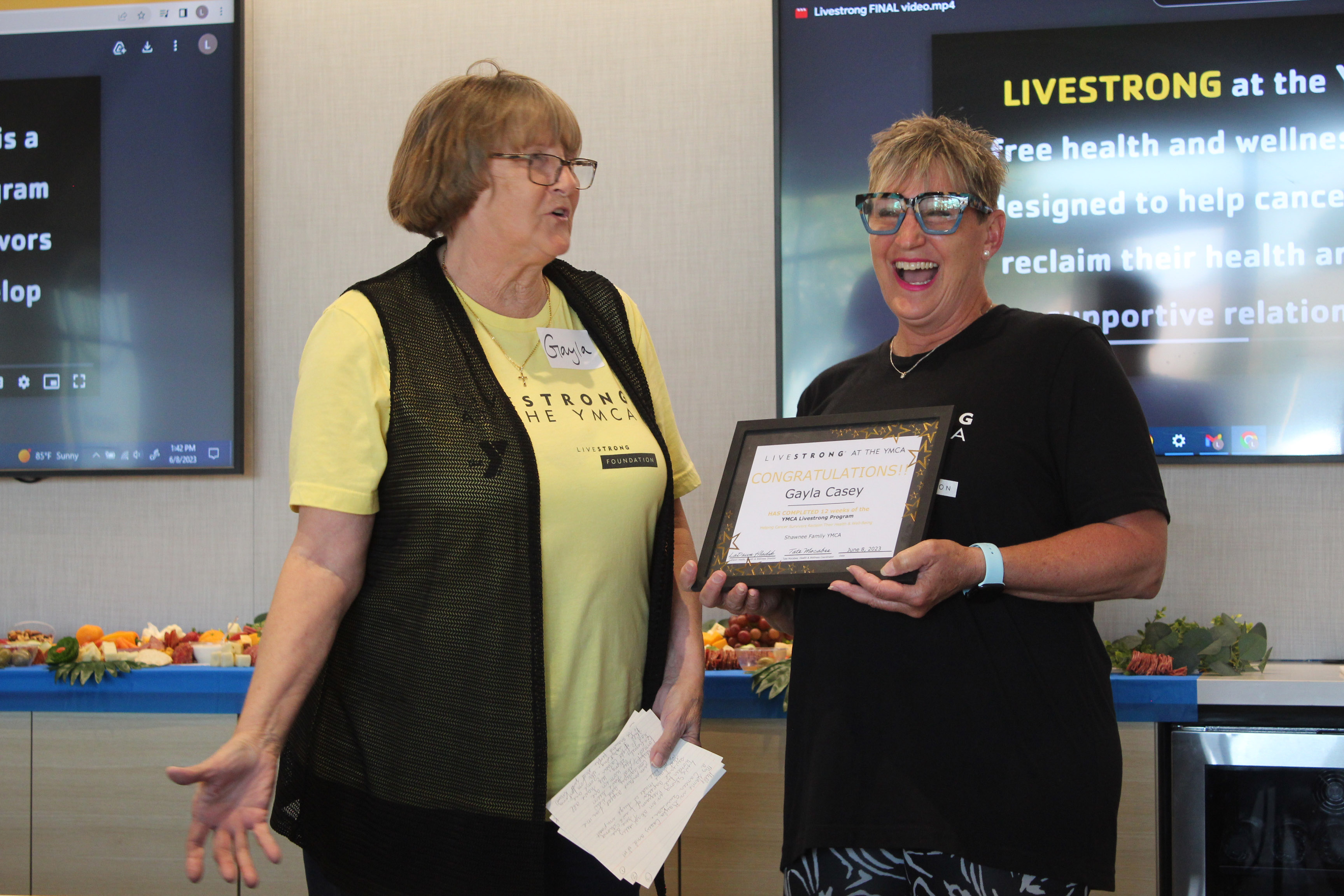 The designated “class clown” Gayla Casey, left, makes YMCA Health and Wellness Director LaDawn Hladik laugh with her stories during the Livestrong Program’s first graduation ceremony, held at First United Bank in Shawnee on June 8. Countywide & Sun/Natasha Dunagan