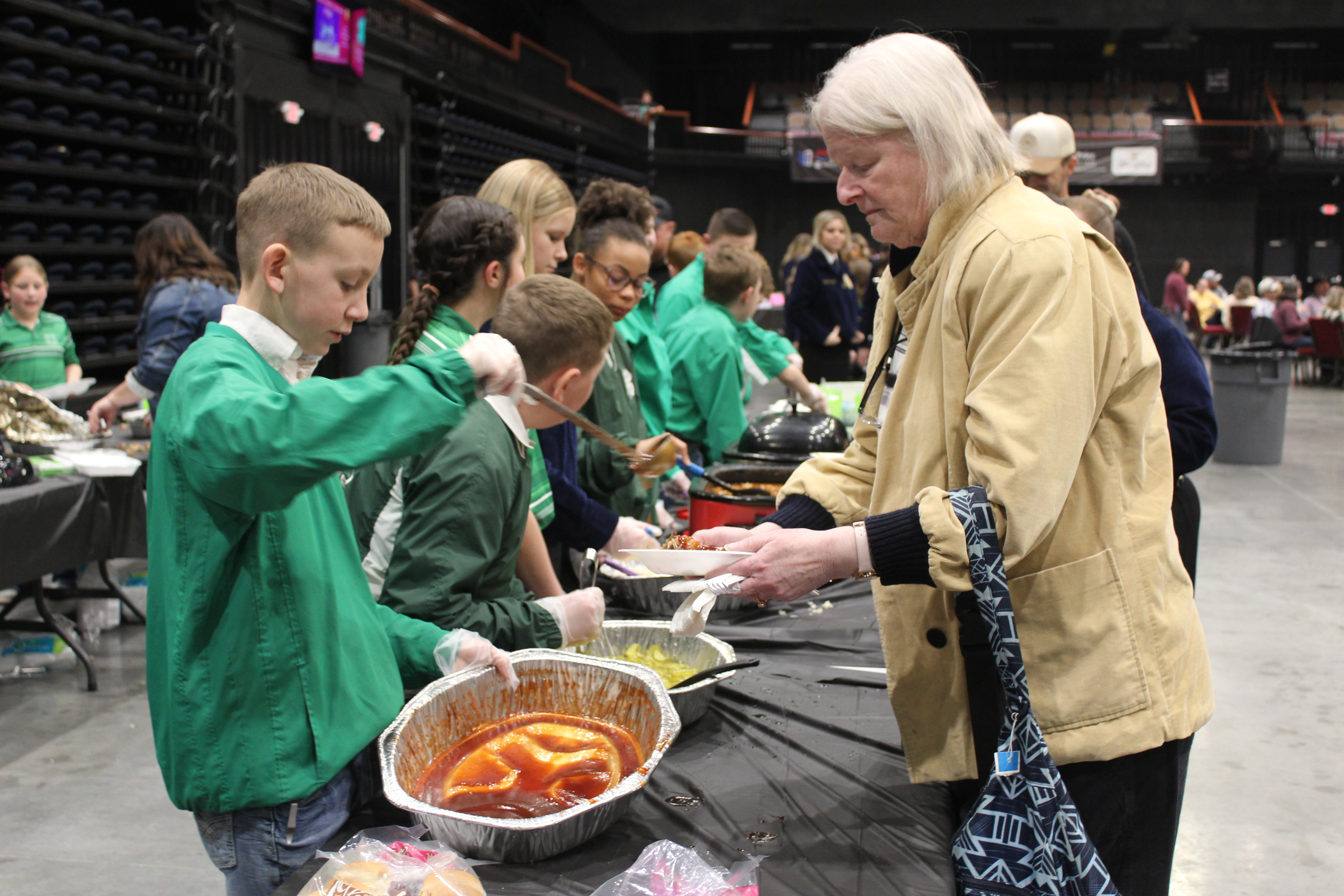 Tecumseh 4-H member Preston Haines adds barbecue sauce to Martha Golleher's plate during the 35th Annual PCJLS Pig Roast and Trophy Auction on Feb. 5 at FireLake Arena. The event brought in $60,000 this year. Countywide & Sun/Natasha Dunagan