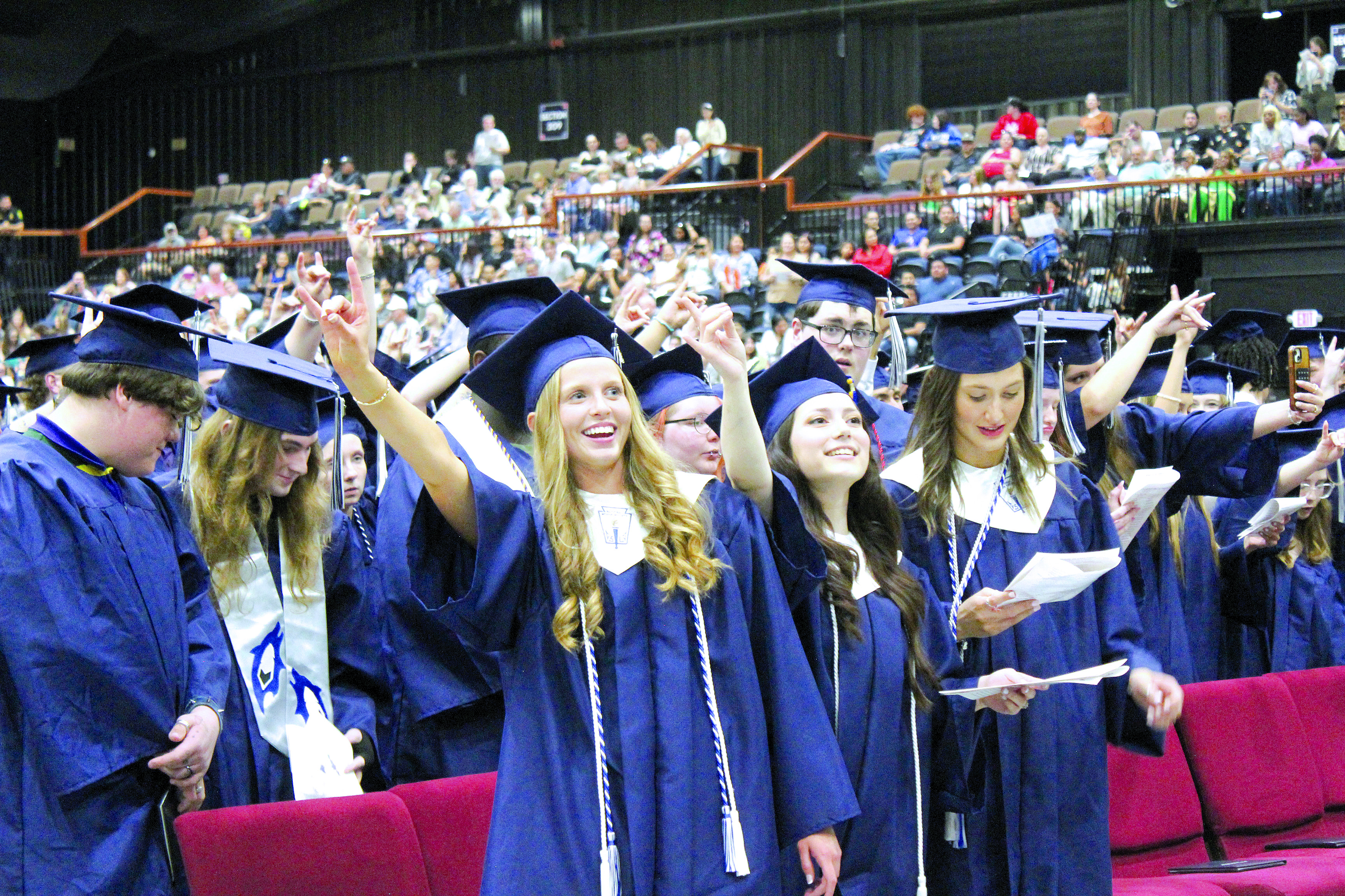 Some of the 186 Shawnee graduates make the sign of the wolf as "Hail, Shawnee High School" is sung by members of the SHS Choir. Shown, in the front row, is Bella Koepke, Holly Valentine and Kennedy Santos. Countywide & Sun/Natasha Dunagan