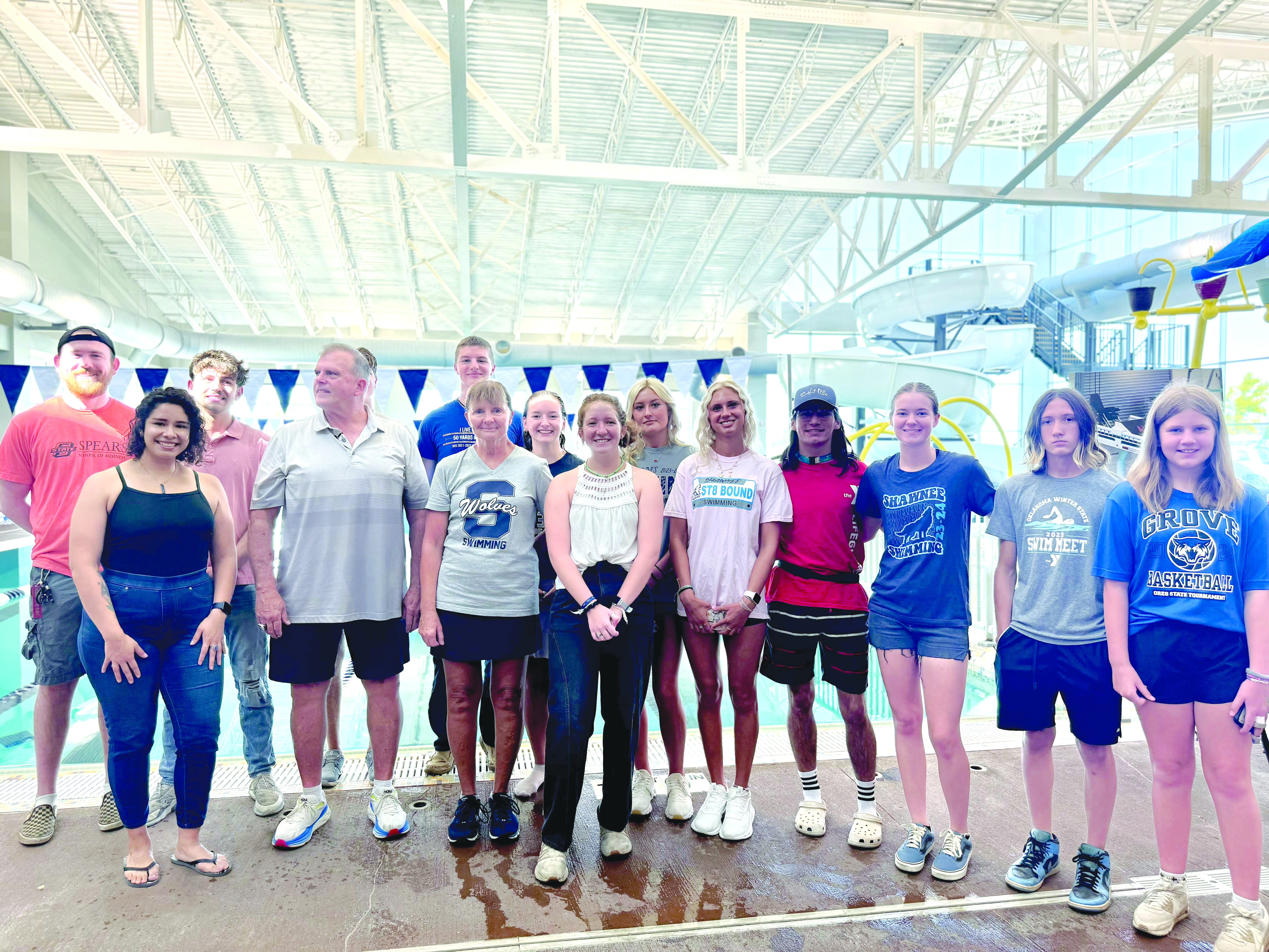 Past and present members of the Shawnee High School Swim Team pose with SHS Assistant Coach Bob McNeil, fourth from left, and SHS Head Swim Coach Valarie Colburn, sixth from left, during the Grand Reopening of the Shawnee YMCA pool on July 13. The SHS swim teams have had to use other pools to practice since the tornado on April 19, 2023, but despite that, the girls team won the state championship this year. Photo provided by Amanda Teape Johnson.