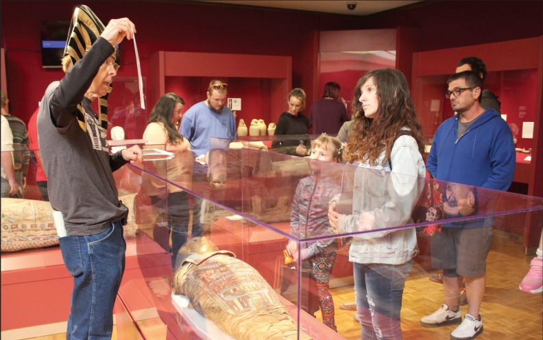 Dressed in a pharoah hat, Mabee-Gerrer Museum of Art Docent Dick Trim speaks about the mummification process, as Princess Tutu lays in front of him, during Mummy Day at the museum on Oct. 26. Tutu was mummified in 332 B.C. in the Faiyum district of Egypt, and was gifted to the Glen Island Museum in 1898, according to https://www.mgmoa-gallery.com/tutu-mummy-cnxk. When that museum went bankrupt, Father Gregory Gerrer purchased Tutu at auction. The MGMOA also has an unidentified mummy from the Roman era.