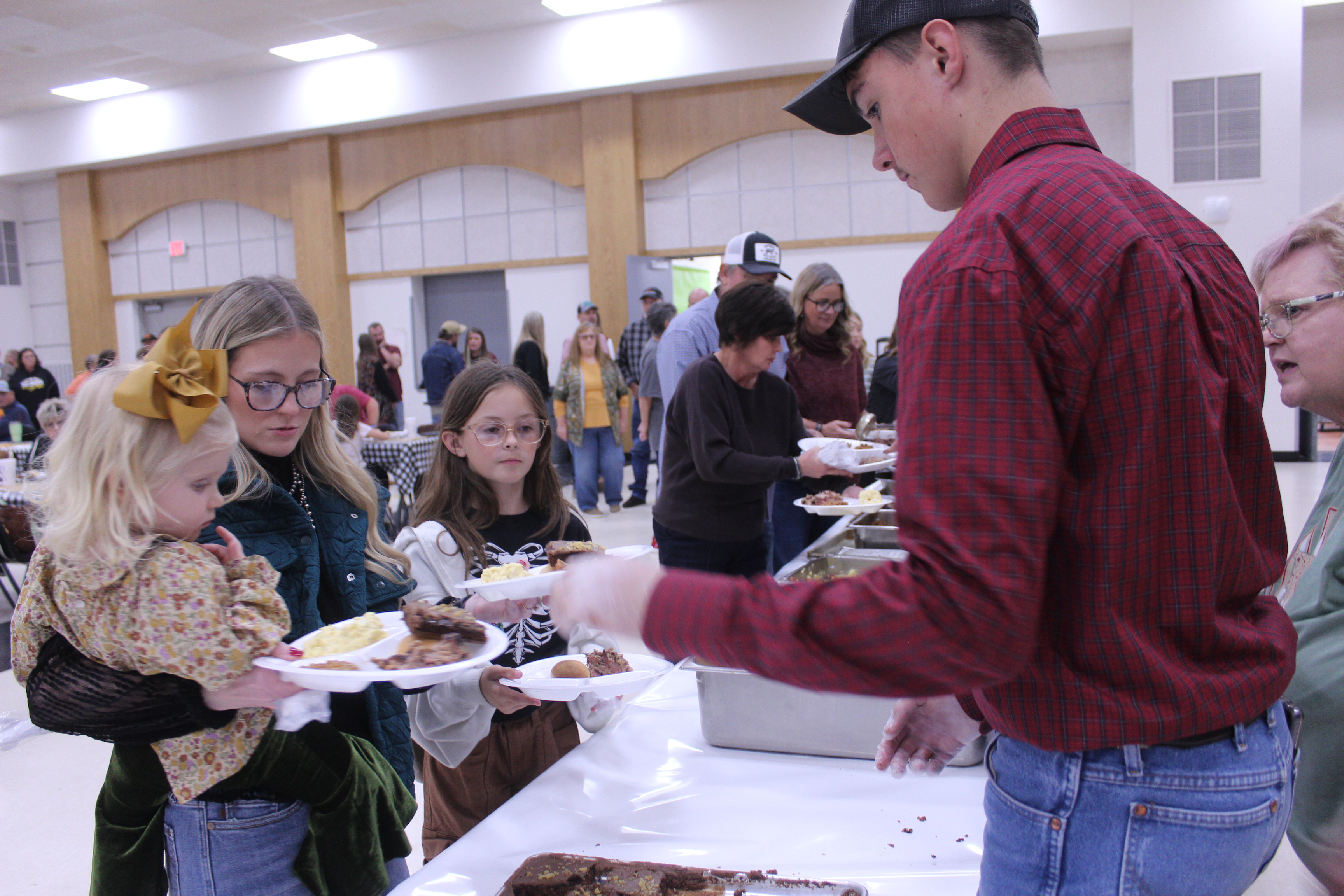 Tecumseh FFA student Lyric Morrison, far right, adds brownies to the plates of Huxlee Newell, 2, of Yukon; THS 2016 grad Hunter Newell; and Presleigh Scott, 10, during the annual Tecumseh FFA Pig Roast, held at the THS Alumni Center on Nov. 21. FFA Advisor Mara Carmen said they sold 225 tickets for the fundraiser. Photos by Natasha Dunagan, Countywide & Sun