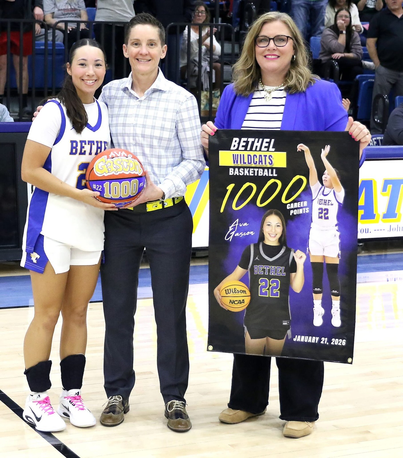 Bethel senior Ava Gascon achieved her 1,000th point at the Jan. 21 game. Shown here, on Feb. 10, Coach Tara Satterfield presents a game ball and Athletic Director Jennifer Lynch holds a banner for Gascon. Photo Provided