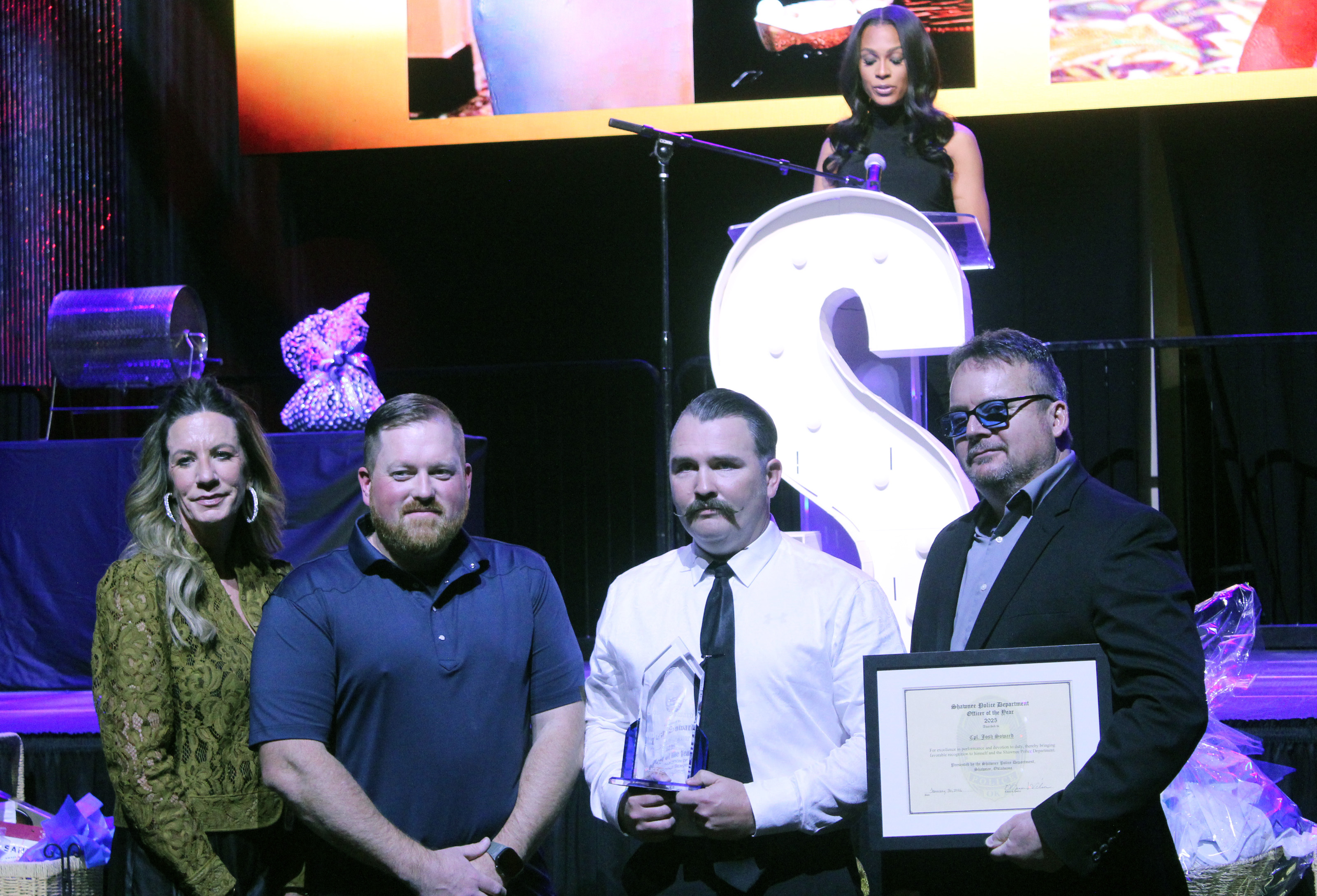 Corporal Josh Soward, third from left, accepts the 2025 Officer of the Year Award Jan. 30 presented by Shawnee Police Foundation Chairman Melissa Stuteville, 2024 Officer of the Year Dennis Rains, and Shawnee Police Chief Mason Wilson. KOCO Channel 5 News Anchor Kylie Walker, on stage, was the emcee for the evening. Natasha Dunagan, Countywide & Sun