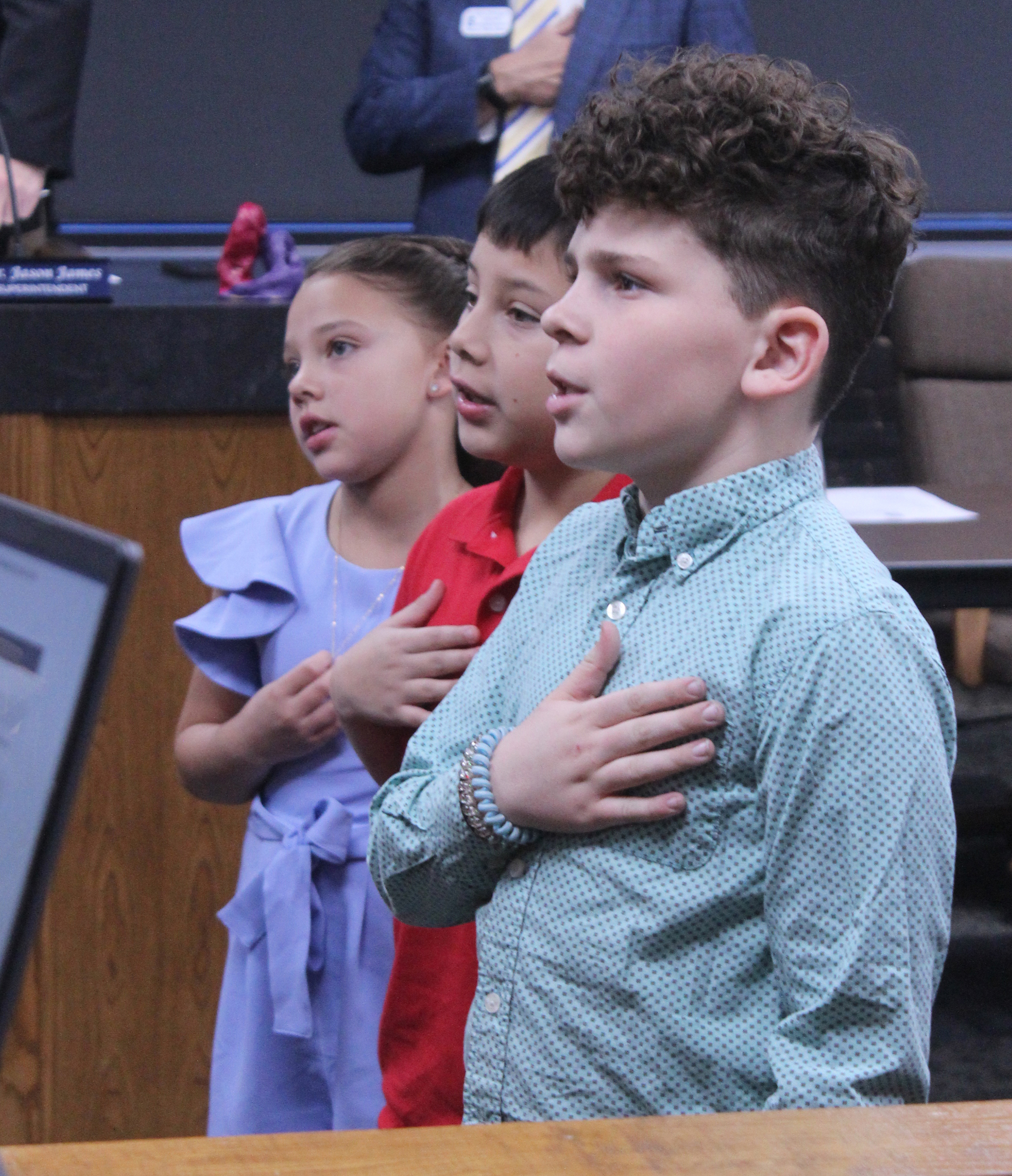 Shawnee students Charlyne Jones, Cordan Jones and Jaxon Wano lead the flag salute to the United States flag during the Feb. 9 Shawnee Board of Education meeting. Natasha Dunagan, Countywide & Sun