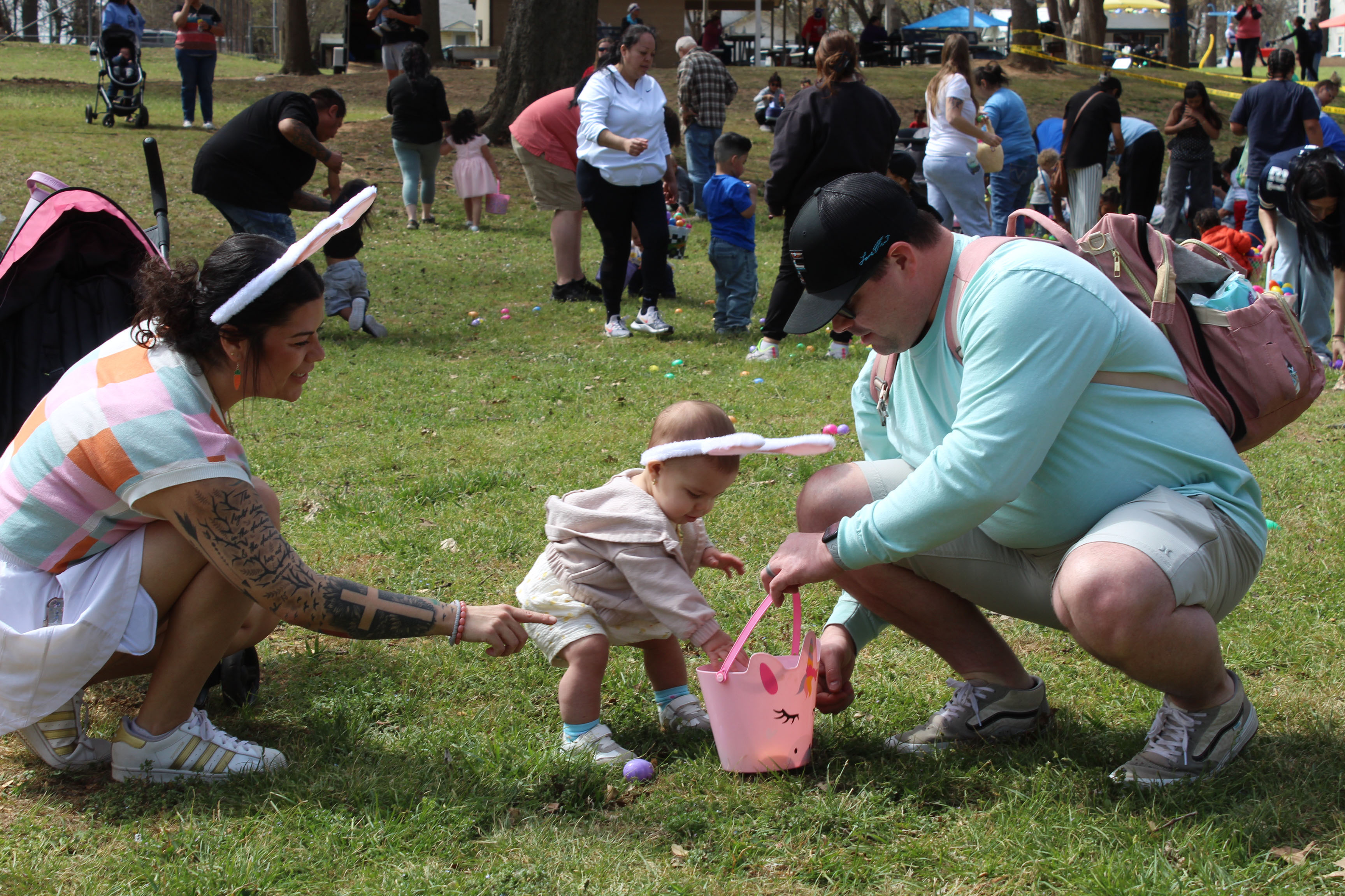 Harmony and Jeremy Brock of Shawnee help their 13-month-old daughter, Talli Brock, to collect eggs on March 28 at Boy Scout Park. The Community Renewal Easter Block Party featured more than 30,000 filled plastic eggs, including those left over from last year when the event was rained out twice, said C.R. Executive Director Brandon Dyer. After being started by local churches, Dyer said one of their members continued the event, which is in its sixth year. See full caption below.