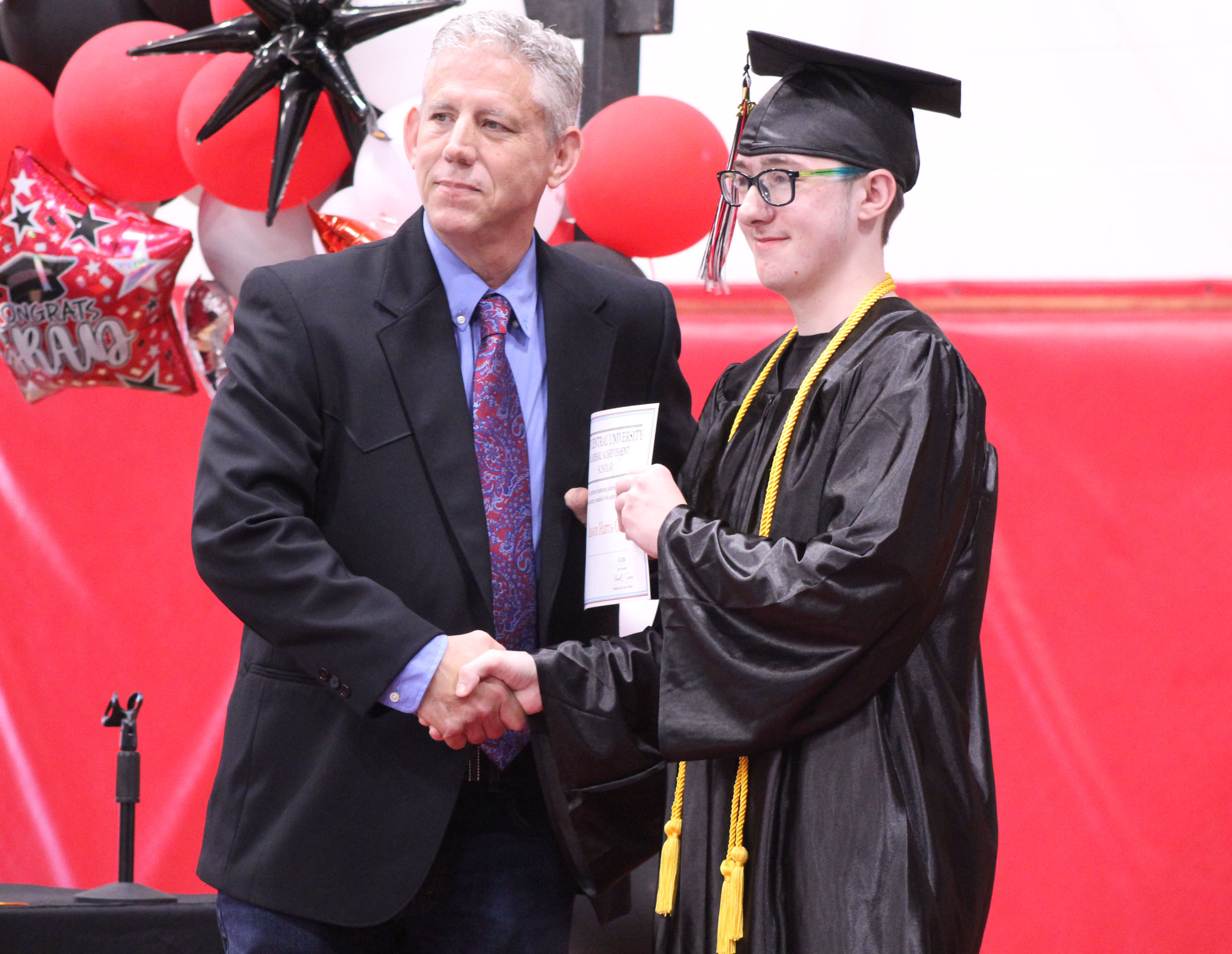 Macomb High School Principal Steve Martin presents an academic scholarship award from East Central University to graduate Jasson Harris-Green during Macomb's Graduation on May 9. Harris-Green was the Salutatorian this year, but Martin spoke about his accomplishments in his place, as Harris-Green chose not to speak. Natasha Dunagan, Countywide & Sun