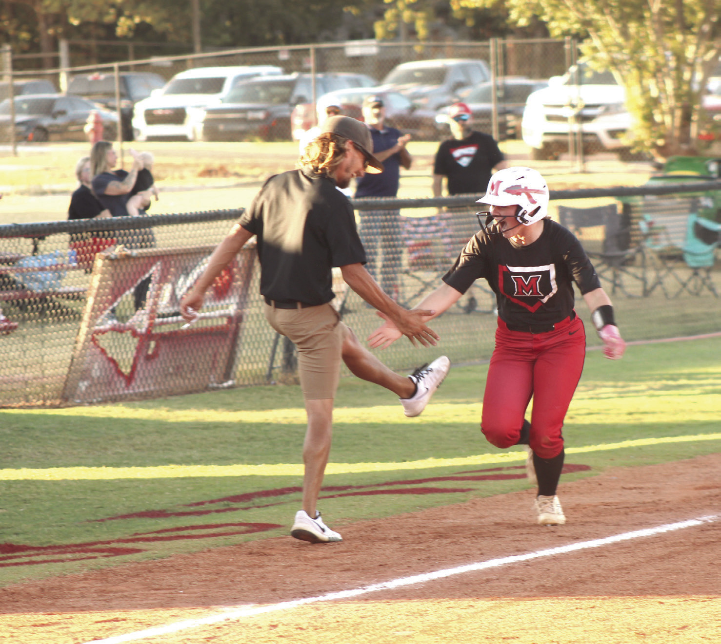 McLoud's Makenzie Lane gets a low five from Head Coach Garrett Hannah after crossing third base on her way to a home run in the Sept. 22 home game against Tecumseh. The Lady Redskins won, 14-4, and have a record of 25-9 so far. Photos by Natasha Dunagan, Countywide & Sun