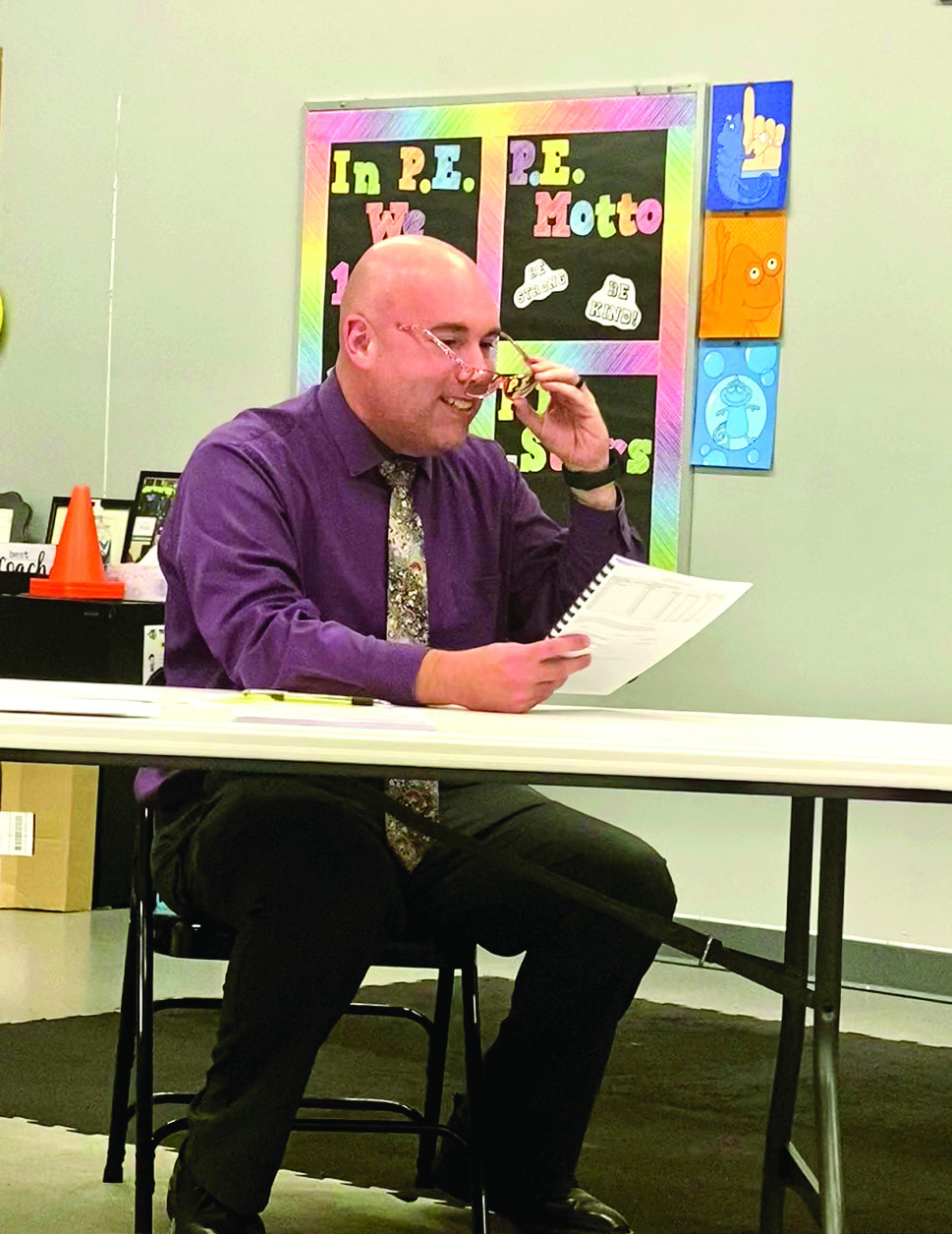 Superintendent Robert Kinsey, with a giggle, borrowed some glasses to read the fine print on the Estimate of Needs document being voted on by the board Sept. 8. Julie Talton, Countywide &amp; Sun