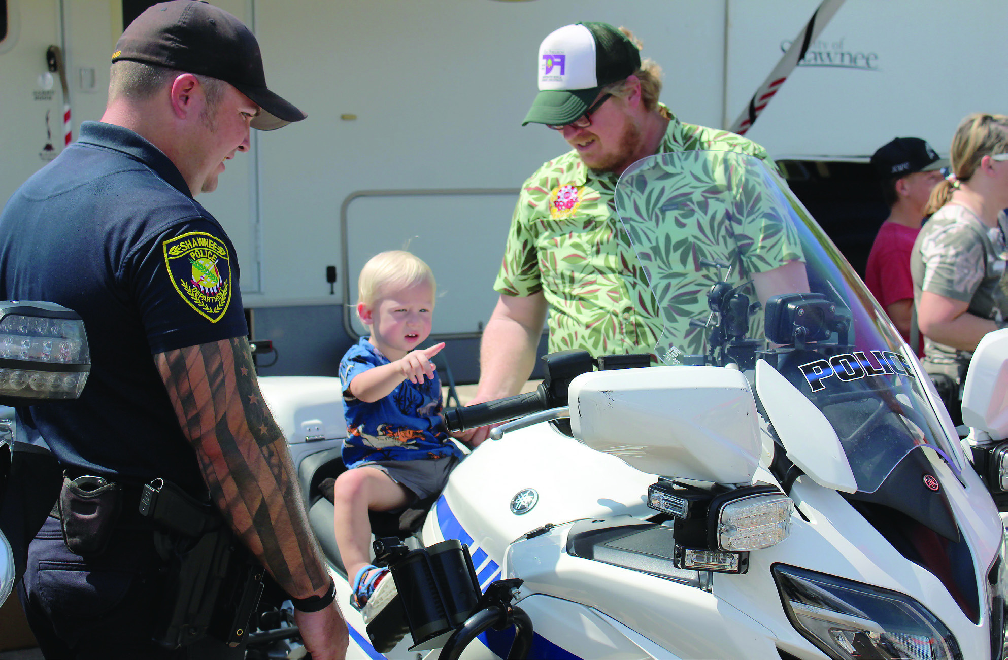 Finley Fry, 17 months, of Shawnee, sits on a Shawnee Police Department motorcycle and points at something, as Corporal Josh Soward, far left, and Fry's father, Matt Fry, keep watch at Cops n' Kids, held on Aug. 24, 2024, at the Heart of Oklahoma Expo Center. File photo