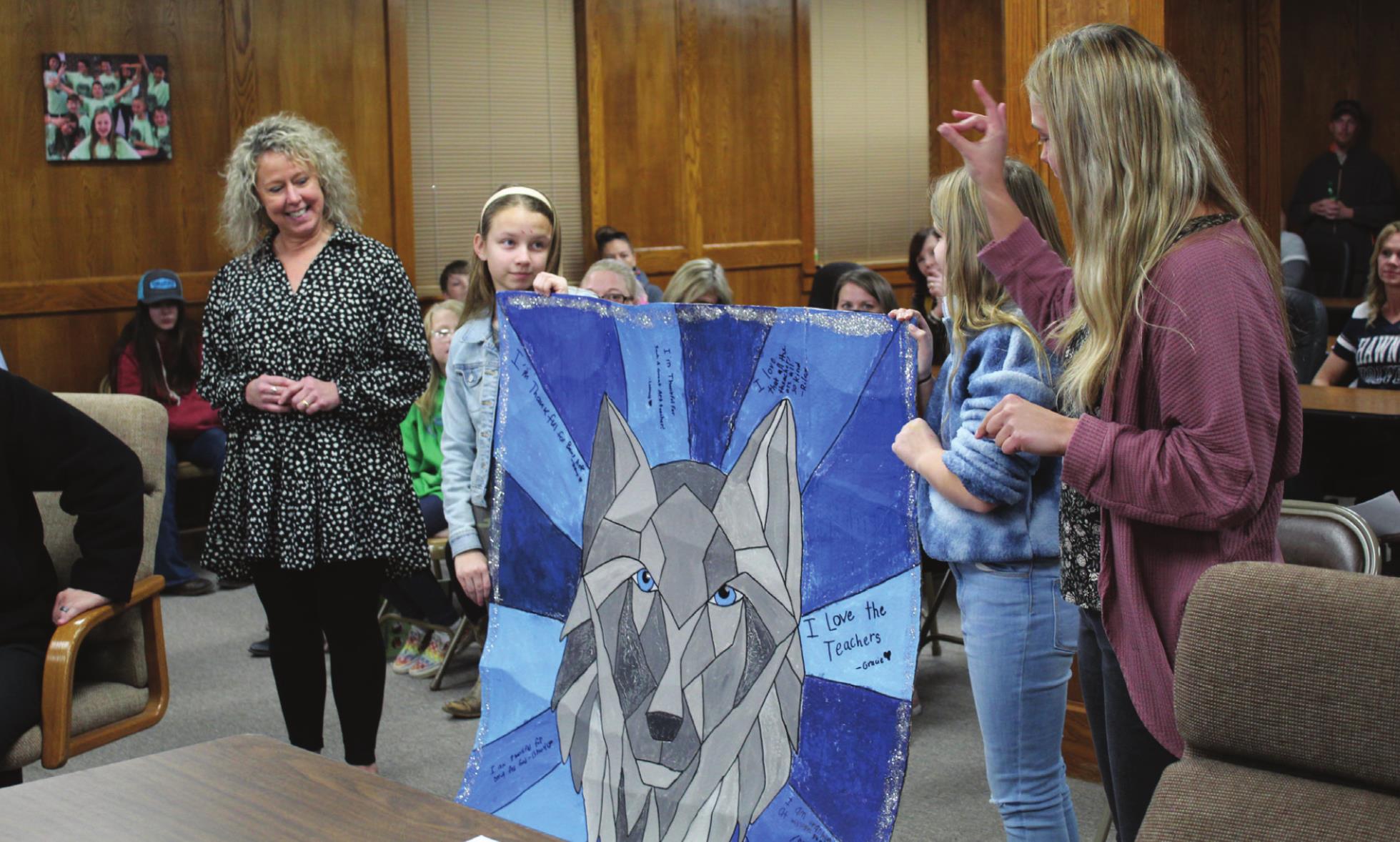 Will Rogers Elementary Principal Jackie Noble, far left, listens as Art Teacher Sidney Smith speaks. Art students Lainey Wilson and Riley Chamblin presented a large, 3D wolf painting, created as a fifth-grade collaboration, to the Shawnee Board of Education on Jan. 10 for School Board Recognition Month. Countywide & Sun/Natasha Dunagan