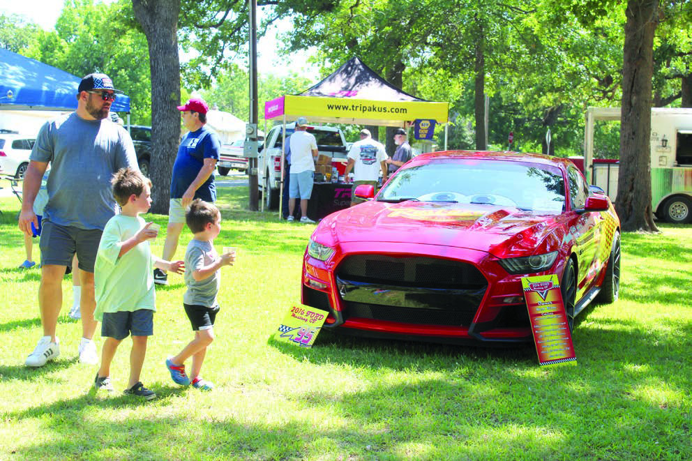David Garrett, Branley Garrett, 6, and Braylon Garrett, 4, all of Shawnee, look over a “Lightning McQueen” 2016 Ford Mustang GT, owned by Mark Wilson of Edmond at the 37th Annual Knights Auto Club Car Show, June 22, at Briscoe Boy Scout/Rotary Park in Shawnee.