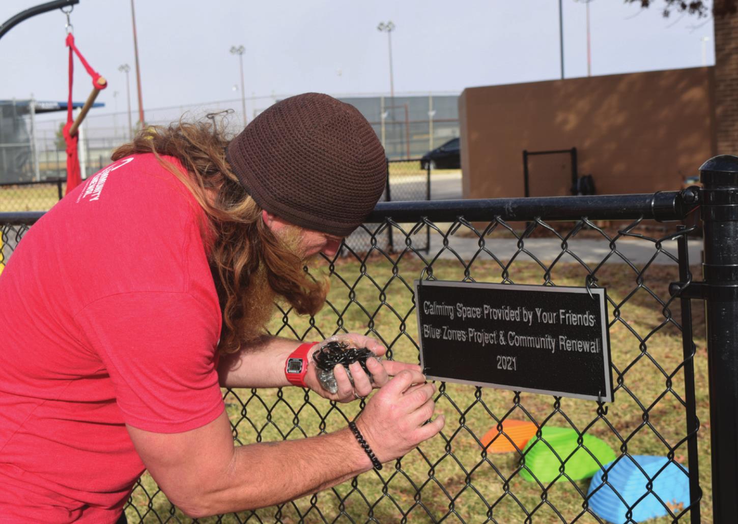 Community Renewal Executive Director Travis Flood attaches a sign to the new fence surrounding the Shawnee High School outdoor “Calming Space” on Dec. 10. Photo provided by Cherity Pennington.