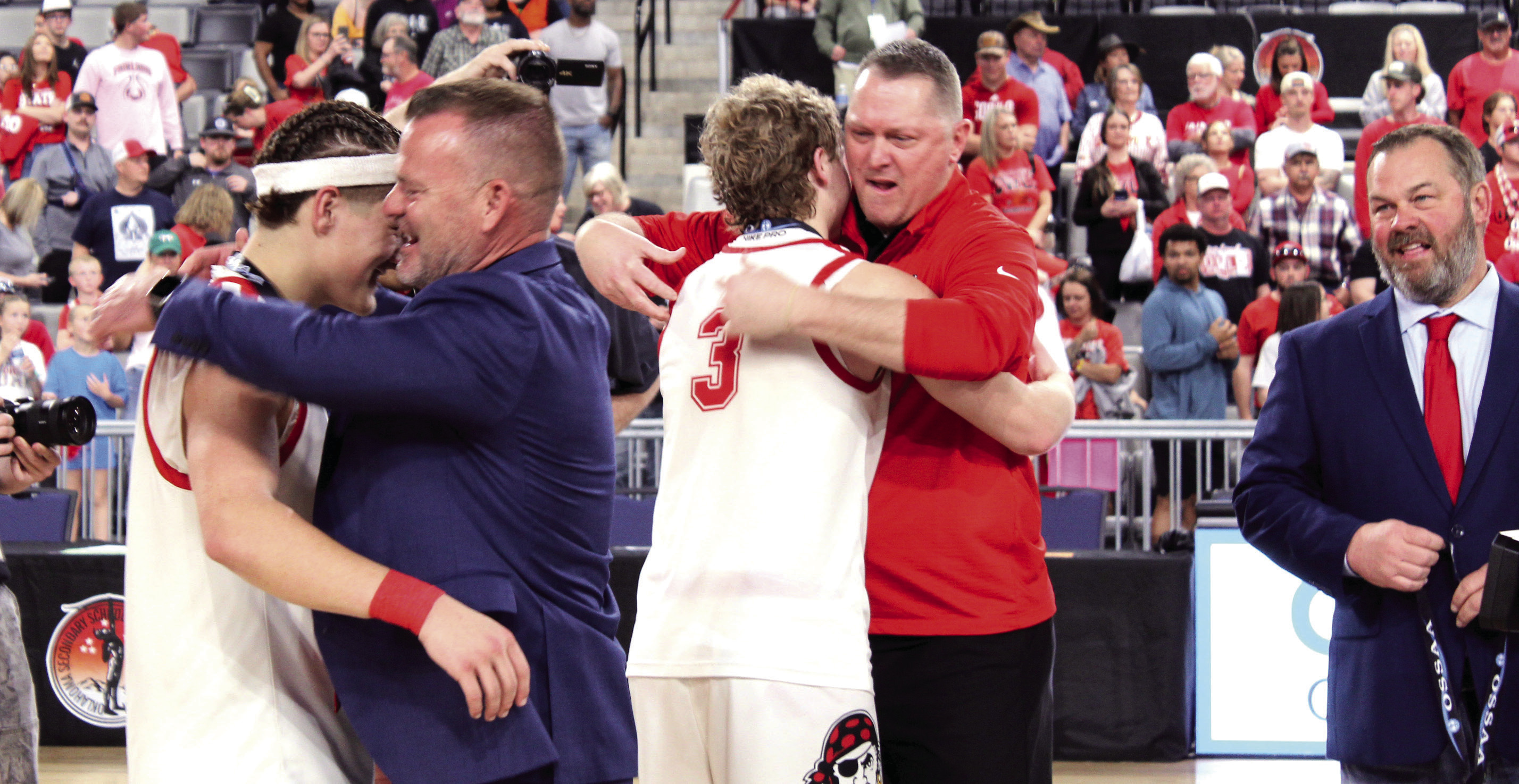Dale Superintendent Will Jones hugs senior Wyatt Seeley, as Assistant Basketball Coach Josh Forsythe hugs his son, senior Denton Forsythe, after the seniors received their Class 2A State Championship medals, following the Pirates' fifth straight victory at the OG&E Coliseum on March 14. Looking on, far right, is Dale High School Principal Erick Muncy. Photos by Natasha Dunagan, Countywide & Sun