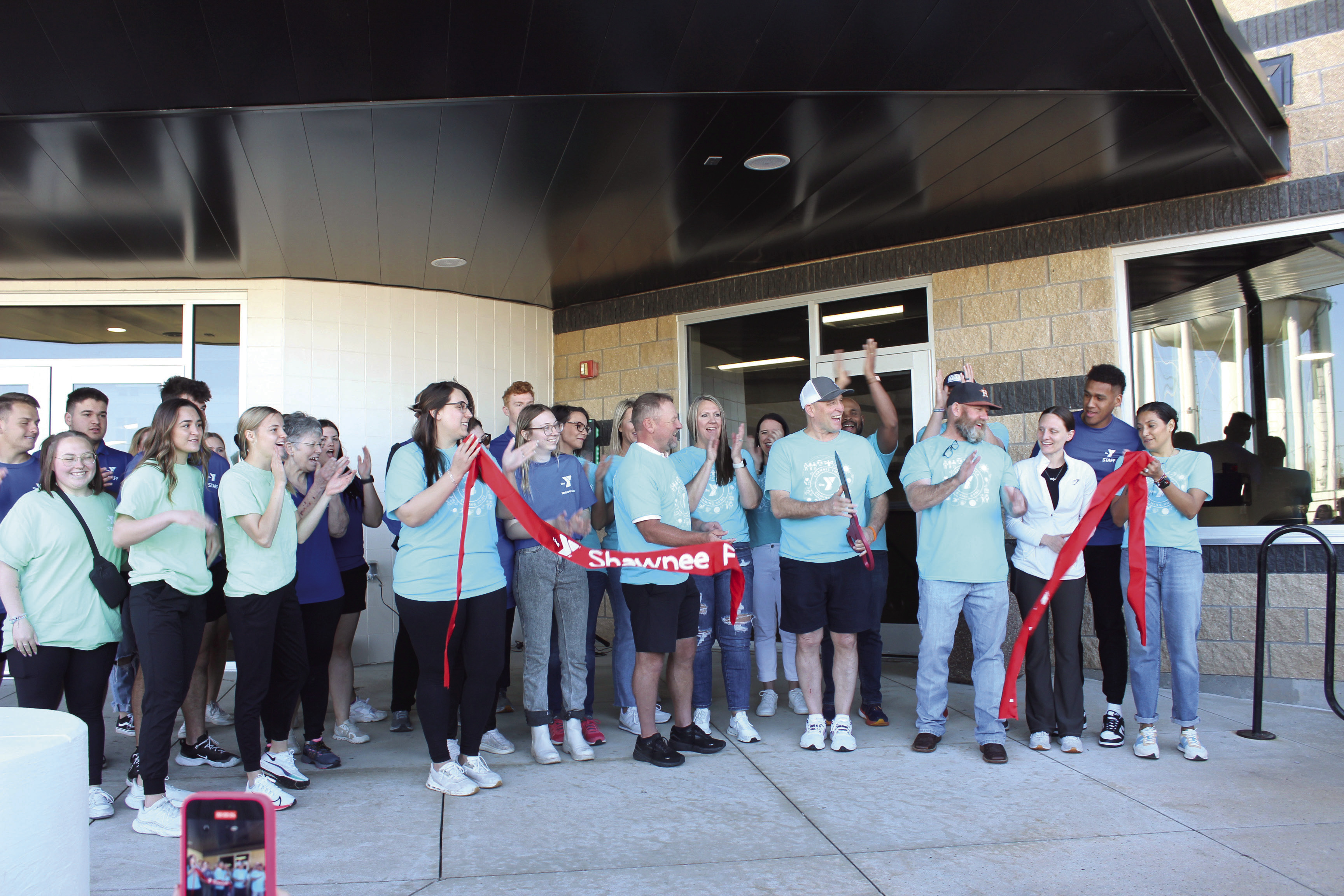 Everyone applauds as Shawnee YMCA CEO Mike Jobe cuts the ribbon, with the help of board members, employees, and others, to officially reopen the Troy and Dollie Smith Family YMCA on April 6, almost a year after it was hit by the April 19, 2023 tornado. Jobe later said approximately 1,800 people attended the Grand Reopening party. File photo