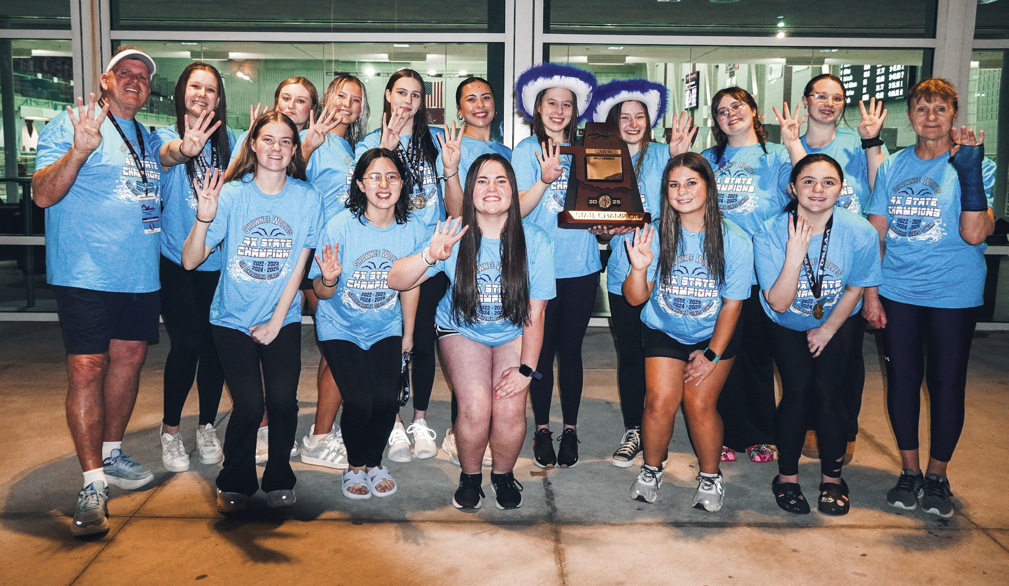 The Shawnee High School Girls Swim Team and their coaches Bob McNeil, far left, and Valarie Colburn, far right, pose with their trophy after winning the OSSAA Class 5A Girls Swimming State Championship at Jenks High School on Feb. 25. This is their fourth state win in a row. Photo provided by Coach Valarie Colburn