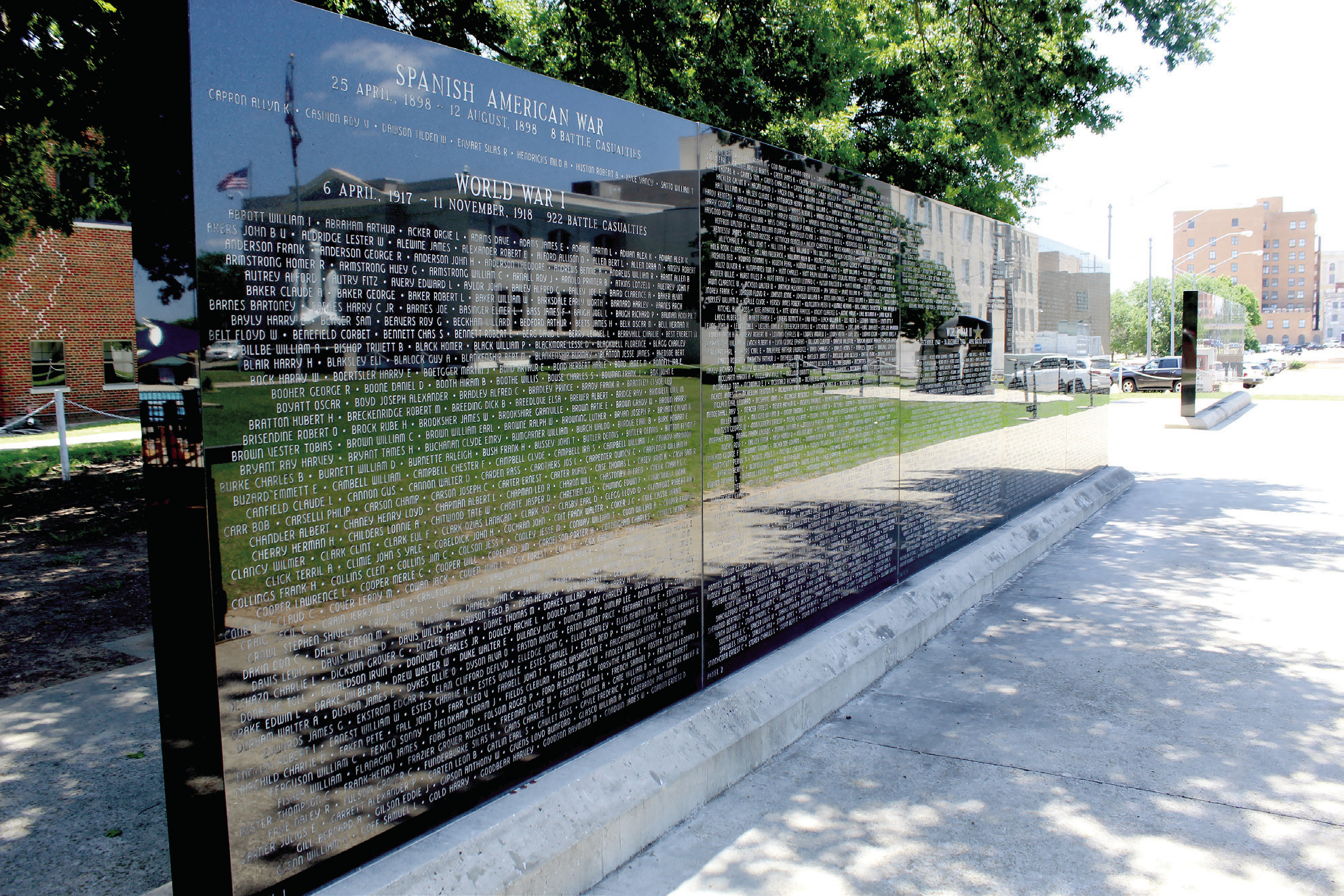 The Pottawatomie County Veterans Educational Museum is reflected in the black granite panels of the Oklahoma Veterans Memorial Wall at the Oklahoma Veterans Memorial in Woodland Veterans Park. Shawnee Veterans Memorial Committee President Bill Ford recently reflected on the history of the memorial park and military museum, and retired Major General Douglas Dollar shared information on the National Society of the Scabbard and Blade opening their headquarters in the museum. 