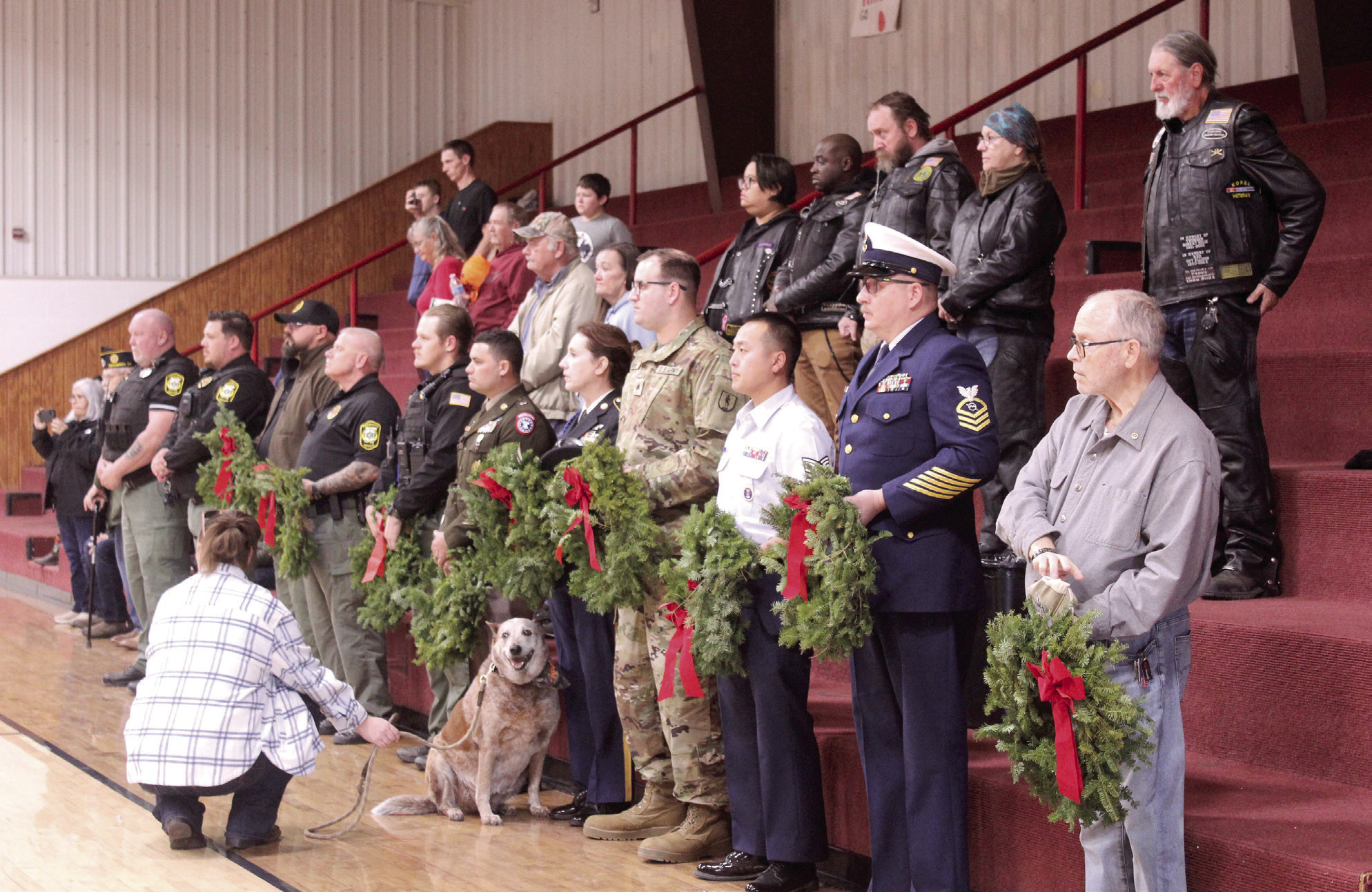 A line of veterans, Sheriff's deputies and a Gold Star father, David Hendrickson, far right, prepare to place wreaths in honor of those lost in each military branch, POW-MIAs, and Gold Star Families during the Wreaths Across America Ceremony, held at Macomb High School gymnasium on Dec. 13. Also shown are members of the Rolling Ambassadors motorcycle club who would place wreaths on the graves of veterans at Prairie View and Romulus cemeteries following the event. See full cutline below.