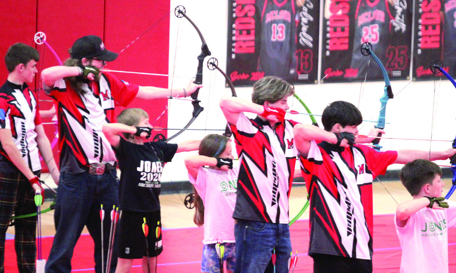 In the red, white and black shirts, from left, Langston Ellison, Dakota Fox, Gunner Moss and Ryan Walls shoot for McLoud High School during the 2026 Oklahoma Centershot Bullseye State Tournament, held at MHS on April 10. Also shown are three archers from Jones. Natasha Dunagan, Countywide &amp; Sun