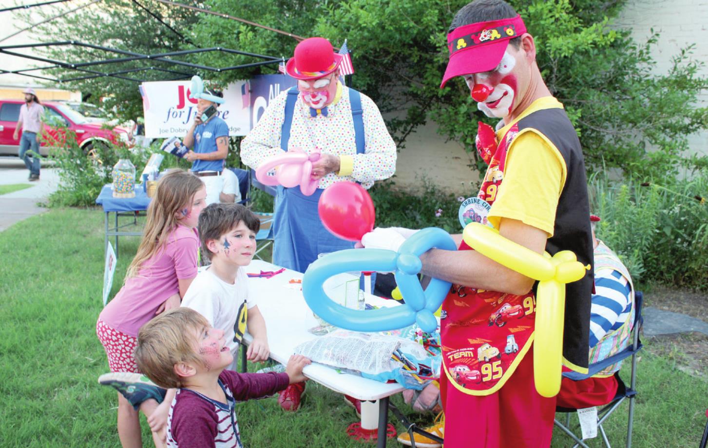 Carolyn McCrary, 9, Ethan McCrary, 7, and Mason McCrary, 5, all of Chandler, get balloon crowns from the India Shriners during the Blues on Broadway event, at Tom Terry Park in Shawnee on June 18. "Salty," aka Mike Byrd, left, and "Pockets," aka Jerry Biffel work on the crowns. Hidden is "Banjo," or John Trivette. Countywide & Sun/Natasha Dunagan