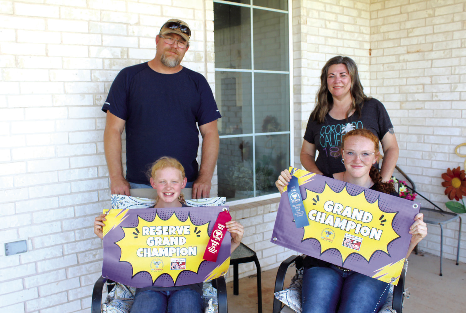 Sisters Callie and Grace Loman, of Bethel, pose with their banners for Reserve Grand Champion and Grand Champion Santa Gertrudis Heifers, which they recently won at the Oklahoma State Fair. Also shown are their parents, Nick and Candace Loman. Countywide & Sun/Natasha Dunagan