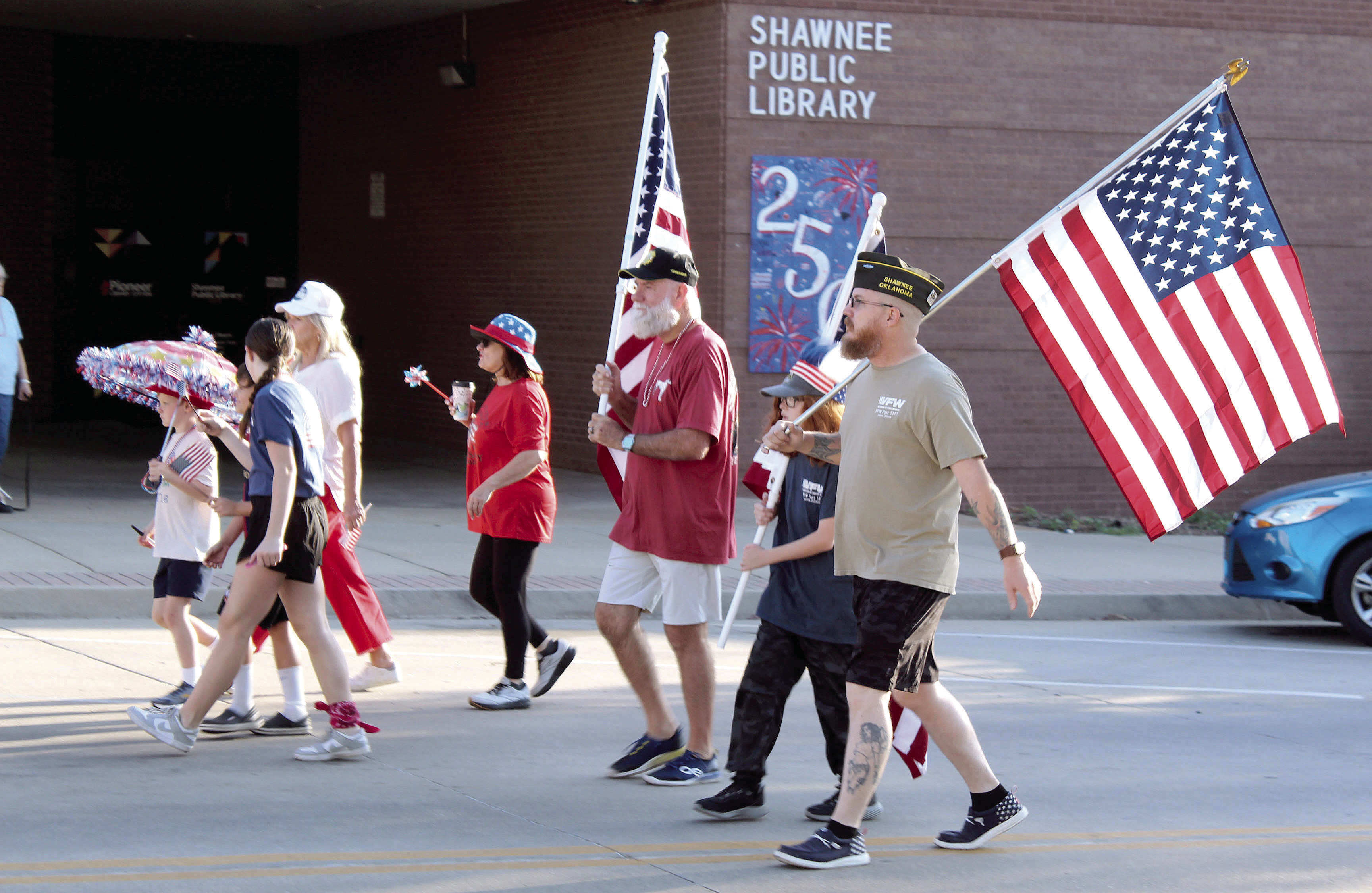 Shawnee VFW members, Past Commander Patrick Koch, Killian Keathley and Michael Keathley, carry flags in the Shawnee Independence Day Parade on July 4. Shown in the background is the Shawnee Public Library's community tile artwork celebrating the 250th USA anniversary. The parade started at the Pottawatomie County Museum at 7:30 am and ended at Woodland Veterans Park with a presentation. Photos by Natasha Dunagan, Countywide & Sun 