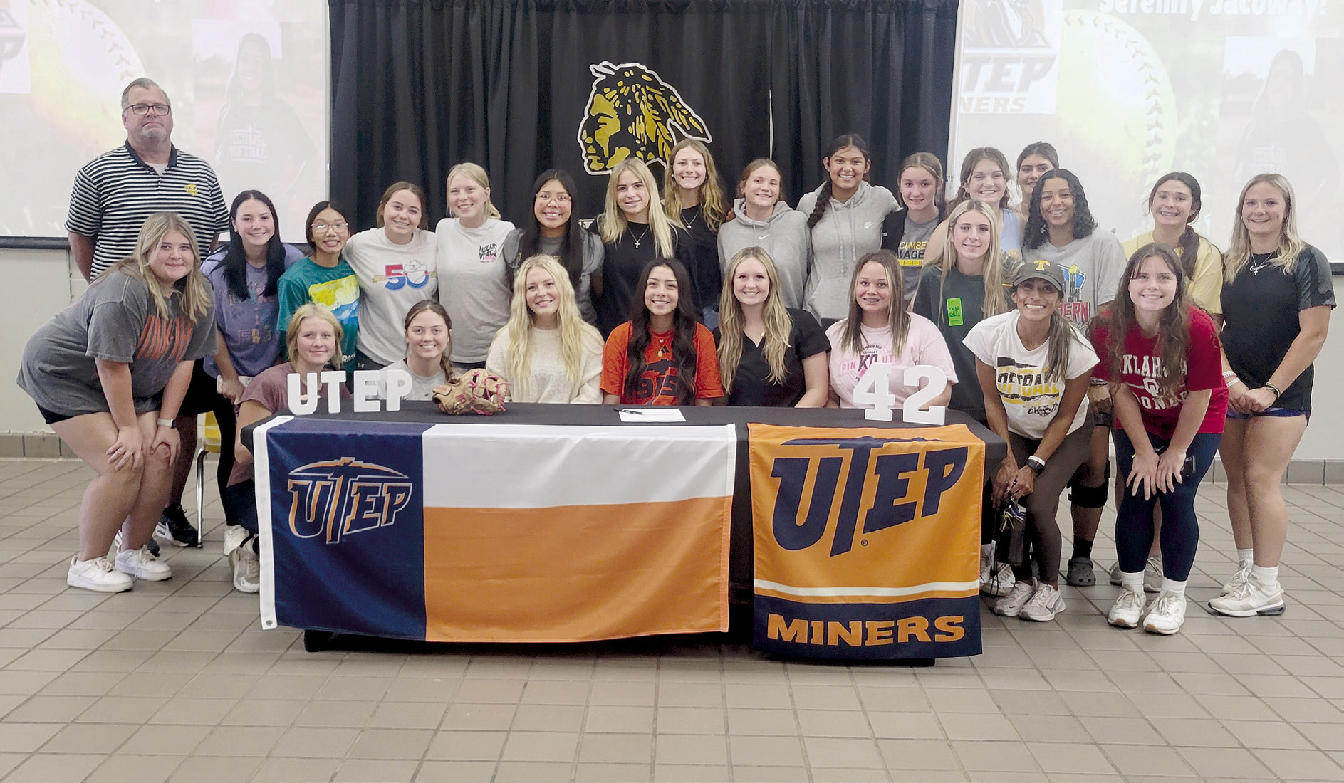 Tecumseh senior Serenity Jacoway, seated fourth from left, poses with the THS softball team and Tecumseh Head Fastpitch Coach Chad Trahan and Coach Kayla Rodriguez. Jacoway signed for softball with the University of Texas at El Paso on Nov. 8. Photo provided by Tracey Forrester.