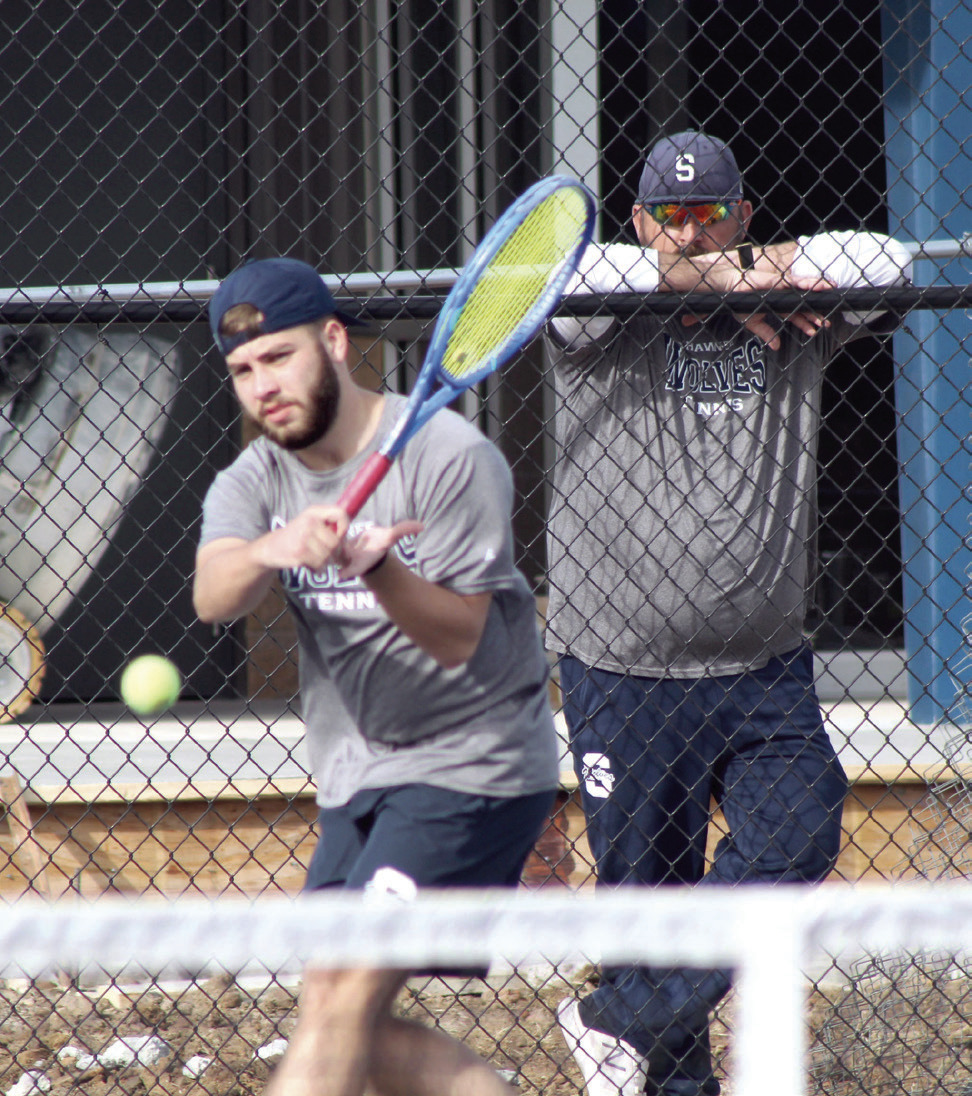Shawnee senior Bryce Comstock returns the ball, as Coach Tyler Harrison watches, during the Tennis Scrimmage against Tecumseh.