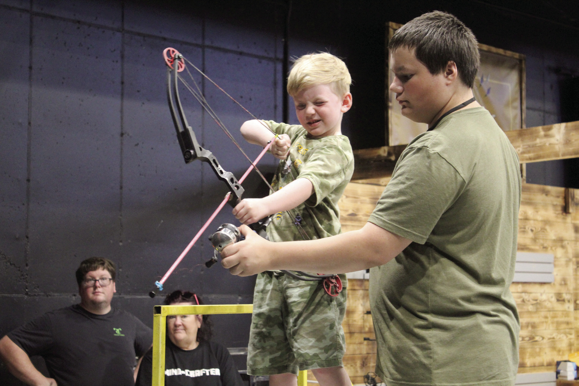 Damian Pearson, 5, of Marlow, is assisted in target bowfishing by Zak McMunn, of Darkwater Adventures in Meeker, during the Outdoor Nation Expo on Aug. 11, 2023 at FireLake Arena. File photo