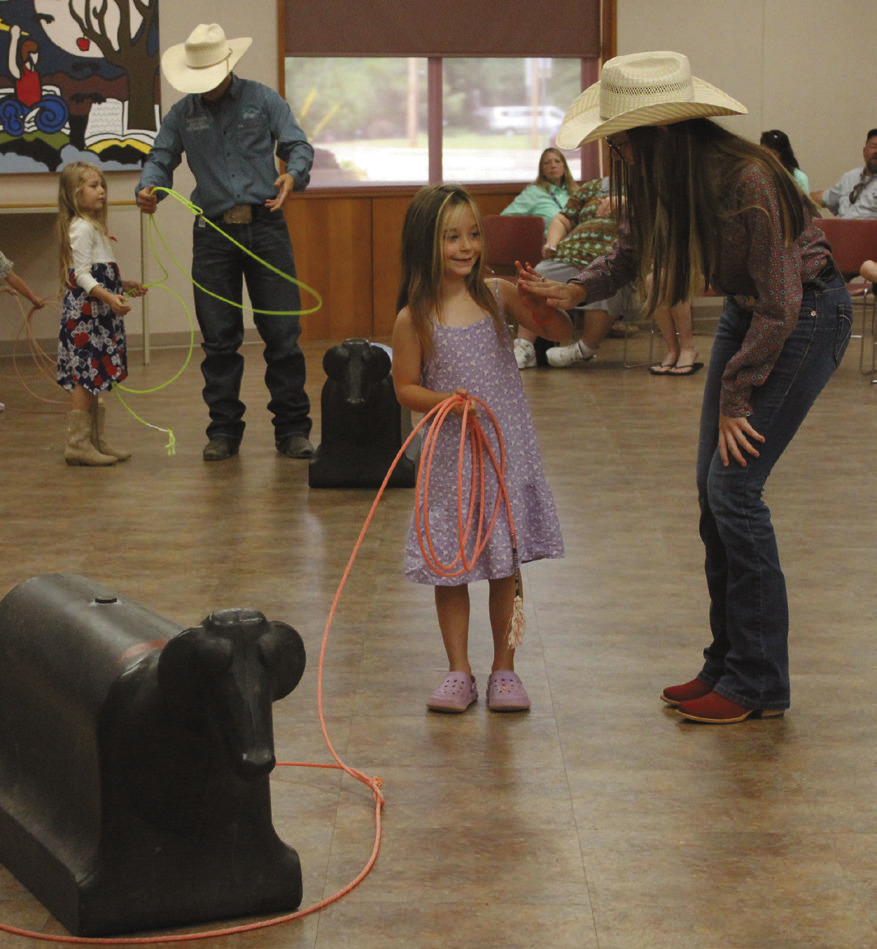 Paula Wiley, 5, of McLoud, gets a high-five from Jasey Graves after learning how to throw a lasso. Also shown is Tatum Roberts, who is helping Isabel Nunes, 6, of Shawnee. Shawnee Public Library Branch Manager Mary Sims said this is the 15th year for six IFYR youth directors to visit the library. Sims also interviewed them about their rodeo experiences, and a 'chuckwagon snack' was provided by Lindsey Cowan, Jennifer Gates and Chloe Gates of the Junior Service League. 