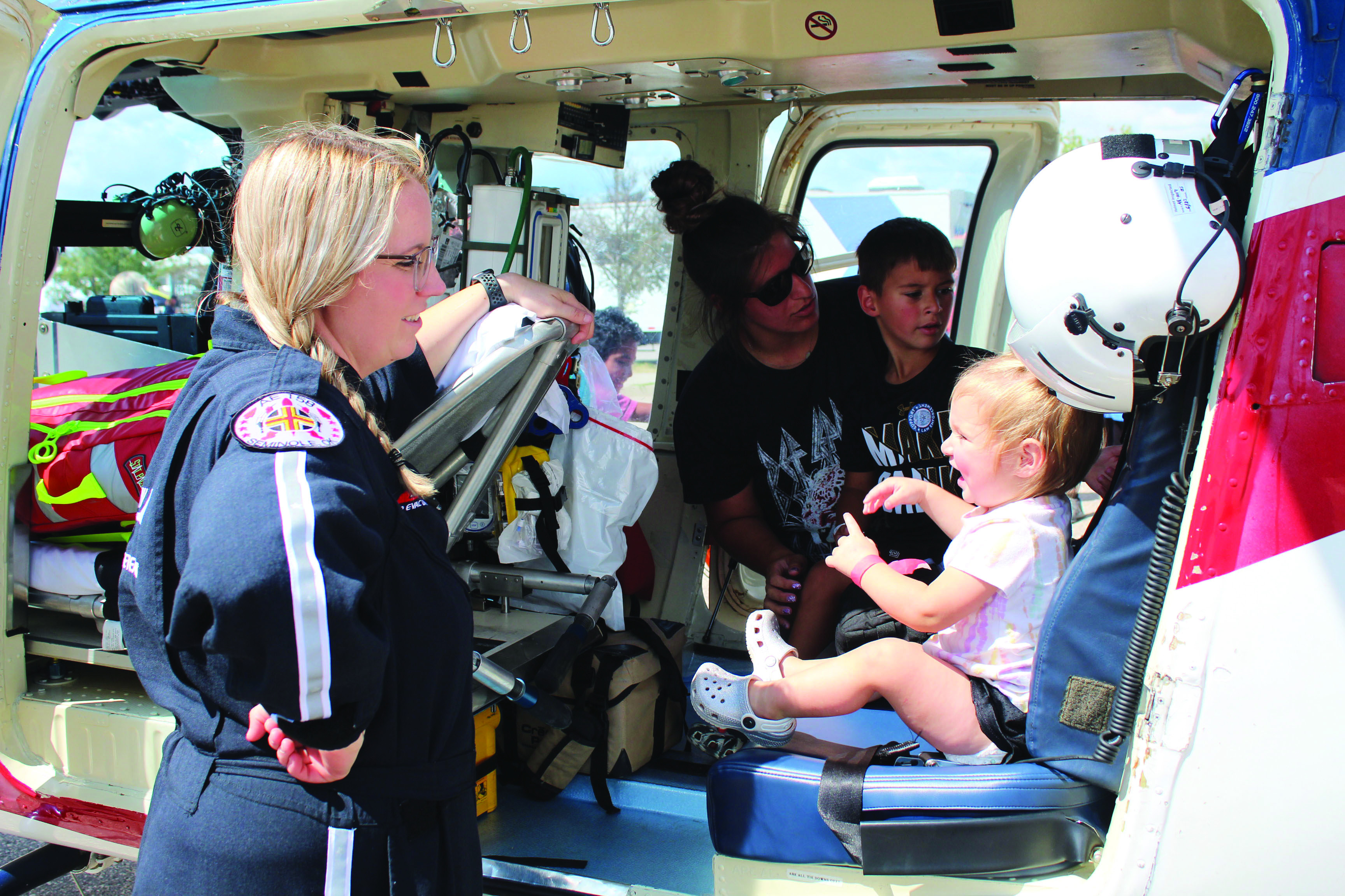 Air Evac Lifeteam Flight Nurse Danielle Siemers, far left, keeps an eye on Tatum Terry, 1, as her mother Jordynn Terry and brother Treyson Terry, 5, all of Shawnee, look at the medical helicopter equipment during Cops n’ Kids on Aug. 27. Countywide &amp; Sun/Natasha Dunagan