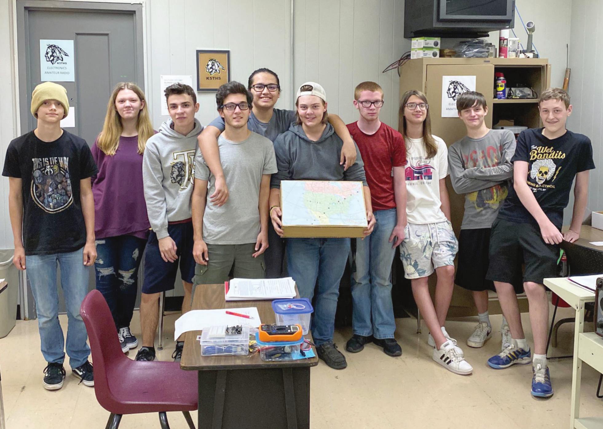 The students from Billy Crow’s Electronics and Amateur Radio Class at Tecumseh Public Schools gather around their map charting the journey of the International Space Station the day the school made radio contact with the station. Photo Provided