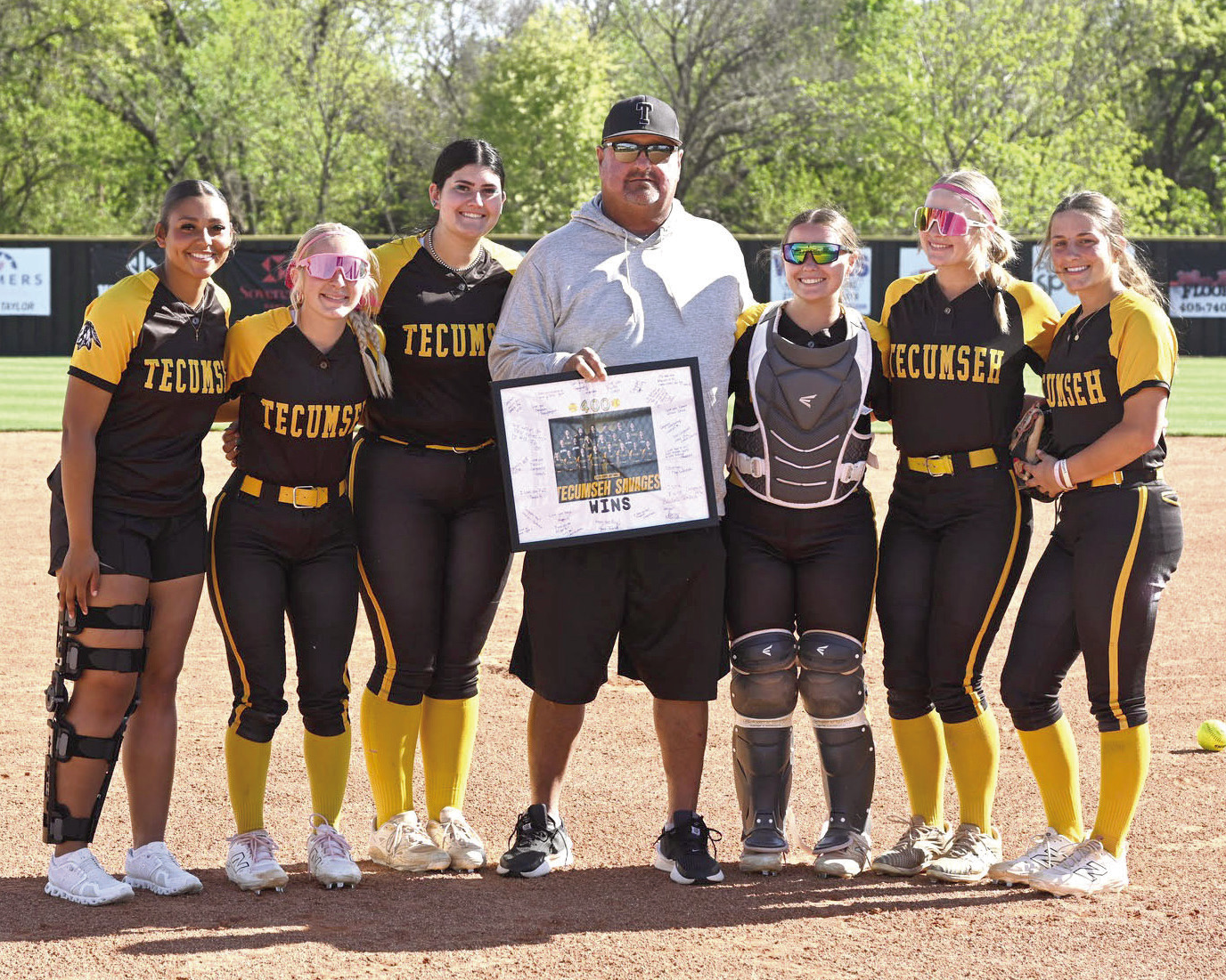 Before the April 7 home game against McLoud, Coach Perry Wilson was presented with a signed, framed photo commemorating his achievement of 400 coaching wins. Wilson is shown here with Tecumseh seniors, from left, Khabrei Simpson, Blakelee Parker, Tylee Brock, Maggie Wilson, Steeli Mitchell and Cadence Leba. Photo courtesy of Kenetta Lisenbee