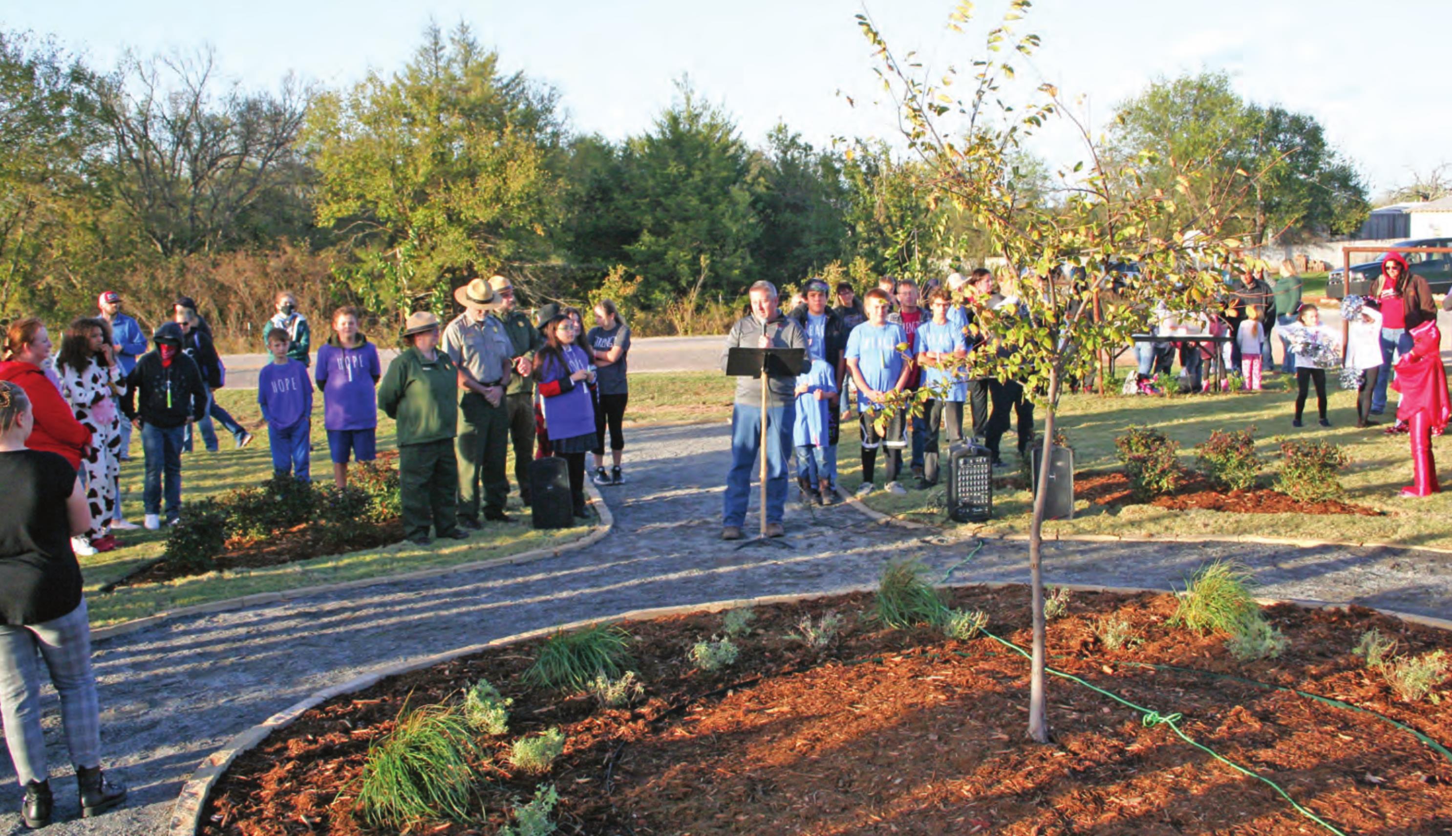 Macomb Public School Superintendent Matthew Riggs (center) speaks at the Reflection Garden dedication, Oct. 28. The tree pictured is at the center of the garden and is a sappling from the Survivor Tree at the Oklahoma City National Memorial. Countywide &amp; Sun/Kendra Johnson