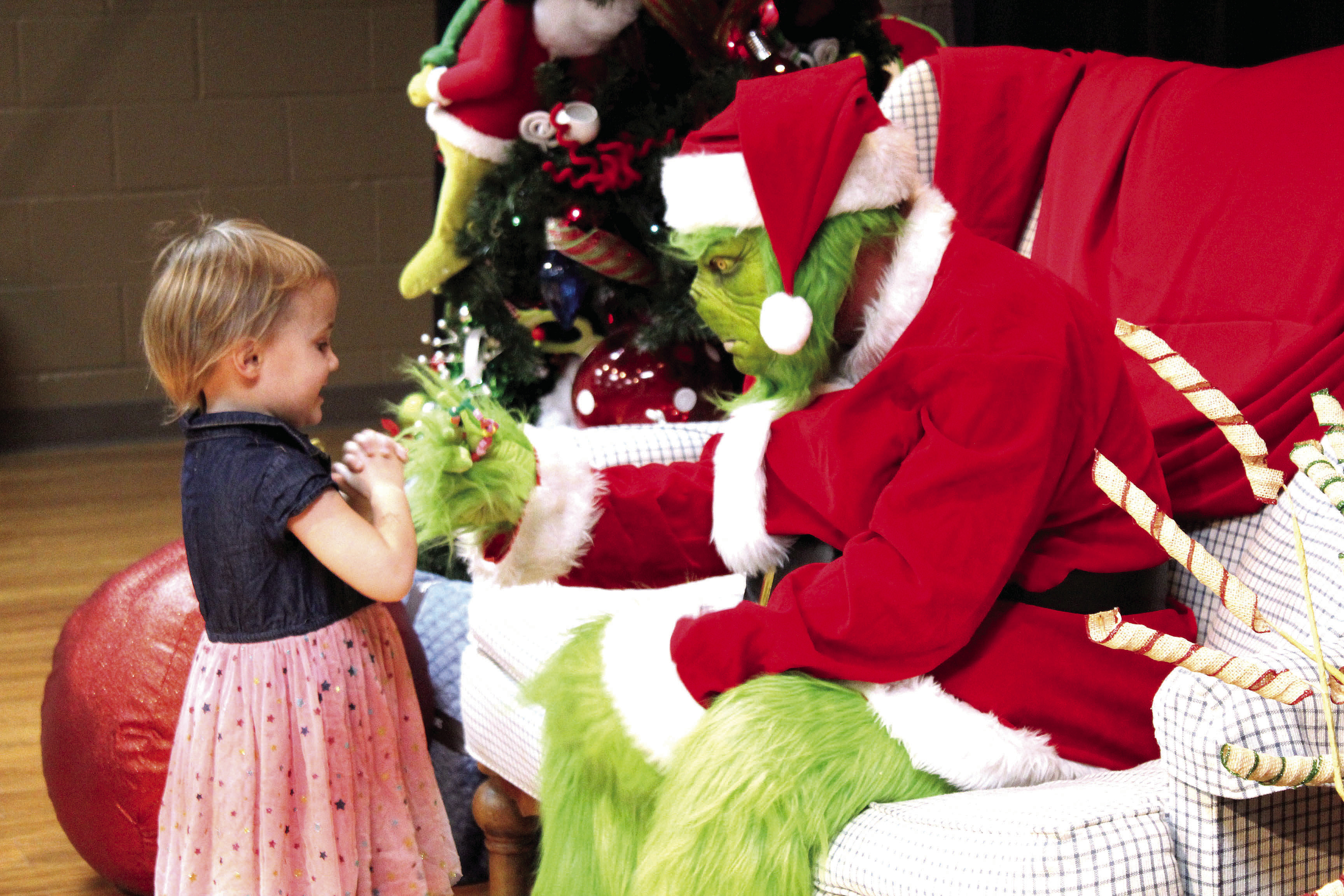 Braivlee Whitmire, 4, of Tecumseh, gives the Grinch a bracelet she made in “Whoville” before getting her picture taken with him on Dec. 8. Tecumseh Public Library employees took and printed around 200 pictures that evening at the Tecumseh City Hall Auditorium, and can be claimed at the library. Countywide &amp; Sun/Natasha Dunagan