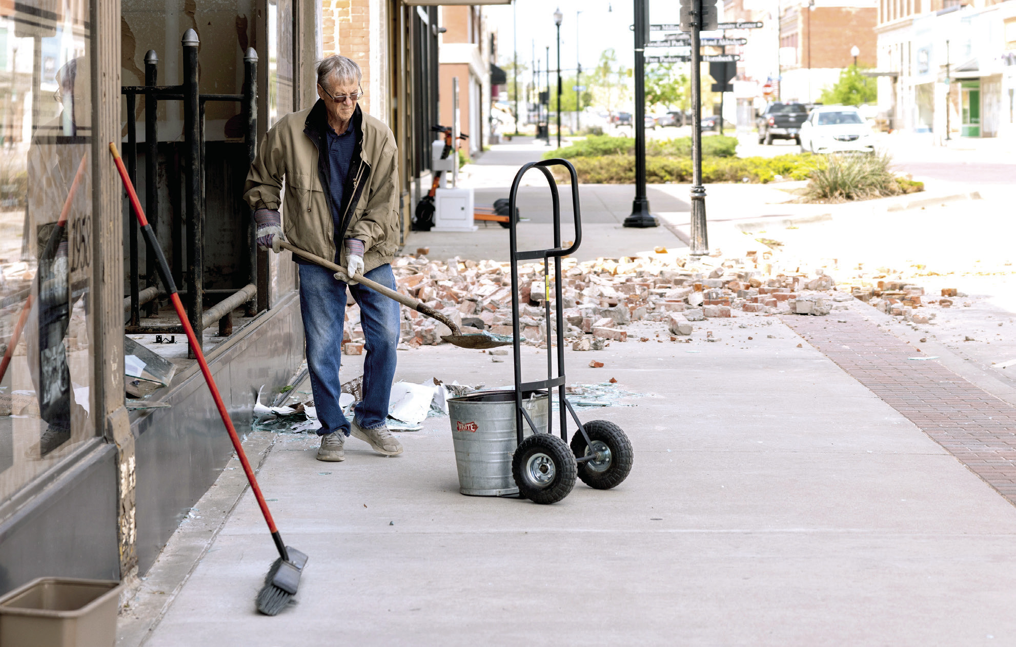 A Shawnee citizen sweeps and clears debris from in front of the Pott County Book Store in downtown Shawnee following the tornado Wednesday night. The front glass of the store as well as the west wall on the second floor was busted out or ripped from the building. Photo provided