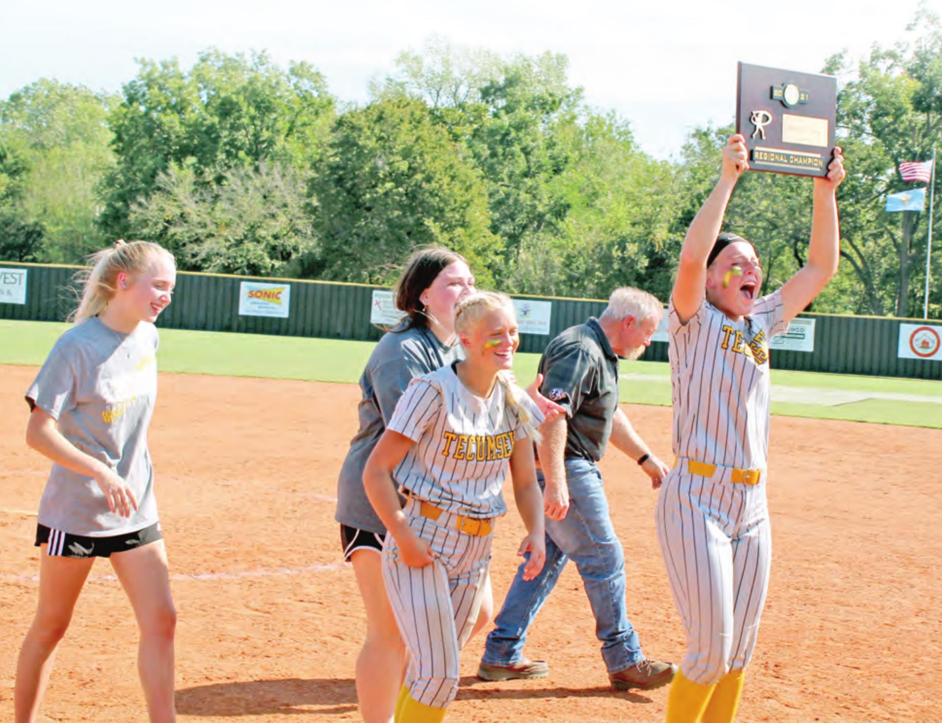 Tecumseh’s Emily Bingham holds up the 4A Fastpitch Softball Regional Champion plaque for the team after it was presented by THS Principal Randy Dilbeck on Oct. 8. Tecumseh won all three of their regional games and advances to state today (Oct. 14) at 11 am. Countywide &amp; Sun/Natasha Dunagan