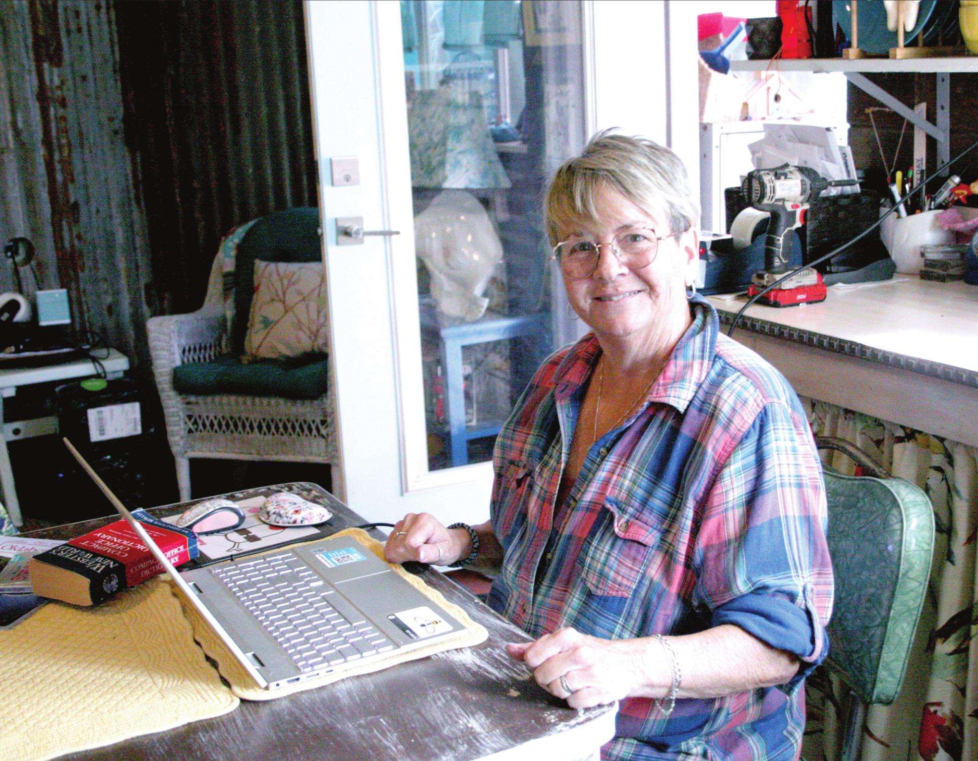 Patti Poteete, writer of the Countywide &amp; Sun’s recurring column, “Sanity’s Last Stand,” poses with the laptop which she writes it on, at her kitchen table. Countywide &amp; Sun/Kendra Johnson