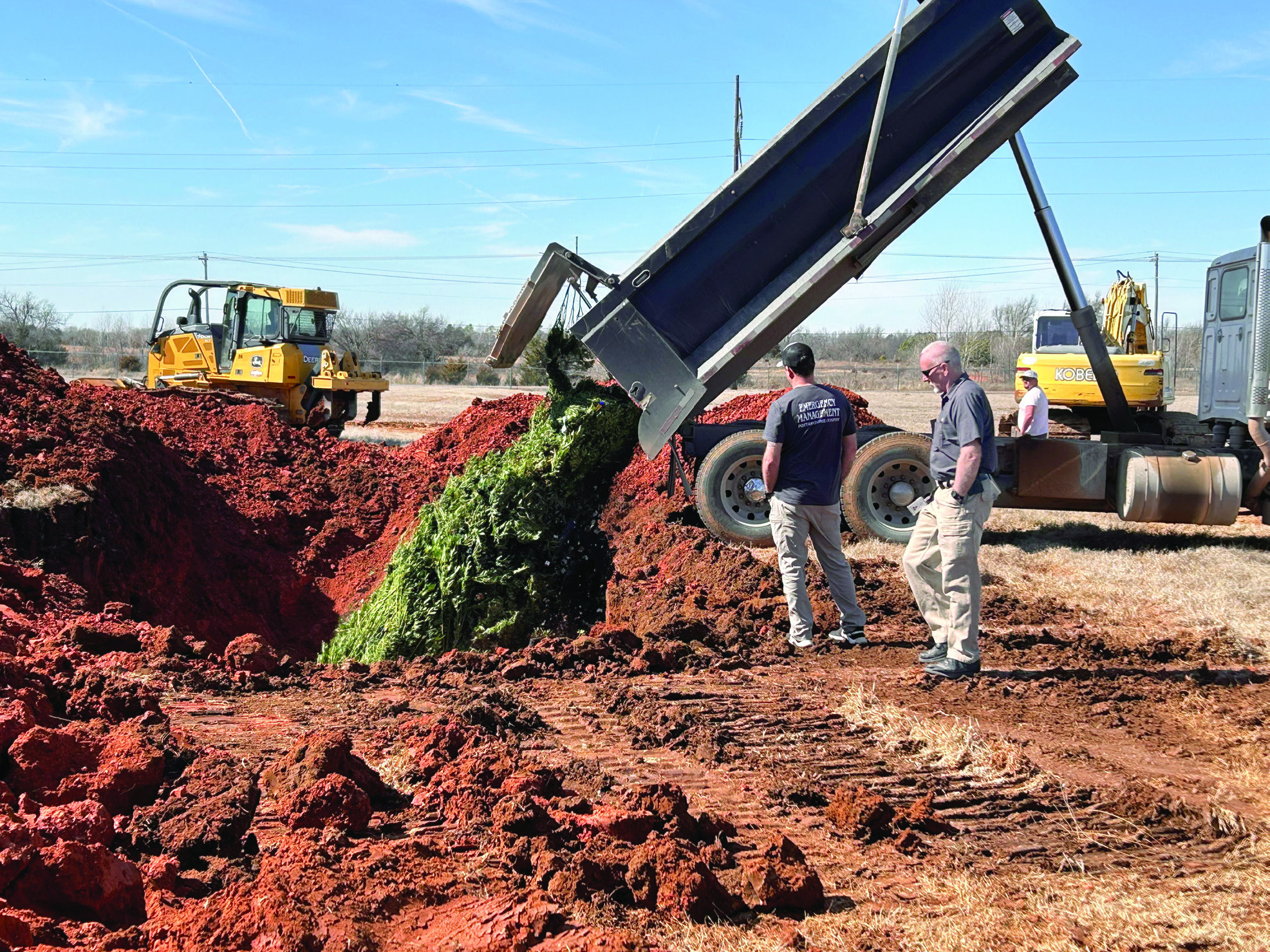 Pottawatomie County Emergency Management Director Chad Larman and volunteer Kurt Shultz watch as the first truck dumps it’s load of marijuana plants into the freshly dug hole. Countywide &amp; Sun/Suzie Campbell