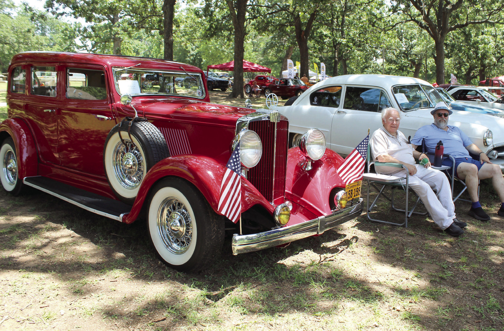 Louis Hopper and his son, Rod Hopper, both of Tecumseh, sit between their rare cars during the 39th Annual Knights Auto Club Car Show at Boy Scout Park on July 27. L. Hopper bought the white 1952 Henry J in 1982, and R. Hopper, who was 15 then, helped to restore it. The red 1932 Hupmobile was purchased by L. Hopper in 1987, and he searched for parts and worked on it for 16 years before he was finally able to drive it.  See full caption below results.