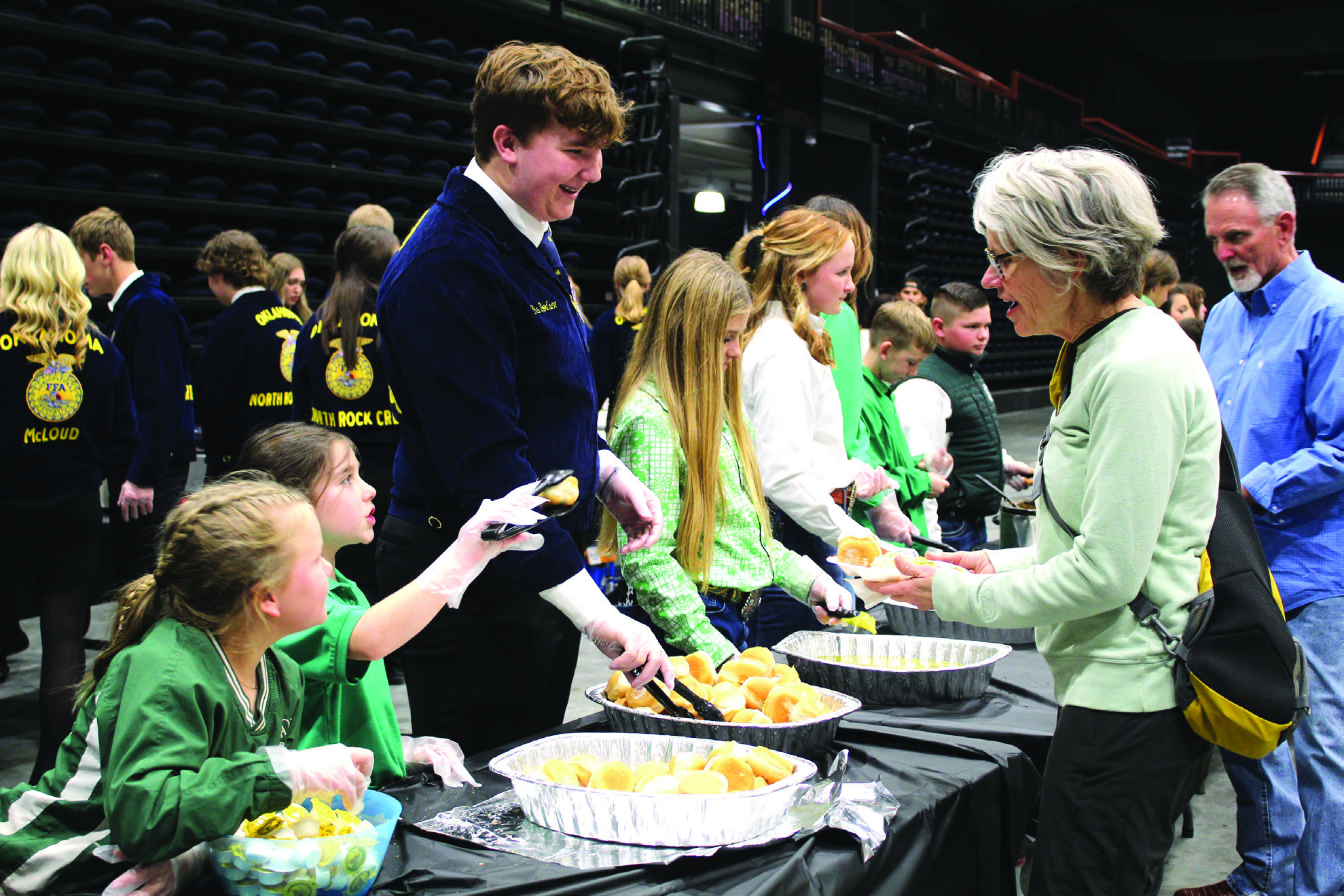 Tecumseh 4-H members Jessi Peacock and Adalyn Seaton and North Rock Creek FFA member Gus Goodson serve Delinda Curtis rolls and butter during the 34th Annual Pottawatomie County Junior Livestock Show Pig Roast and Trophy Auction on Feb. 6, 2023. Natasha Dunagan, Countywide &amp; Sun