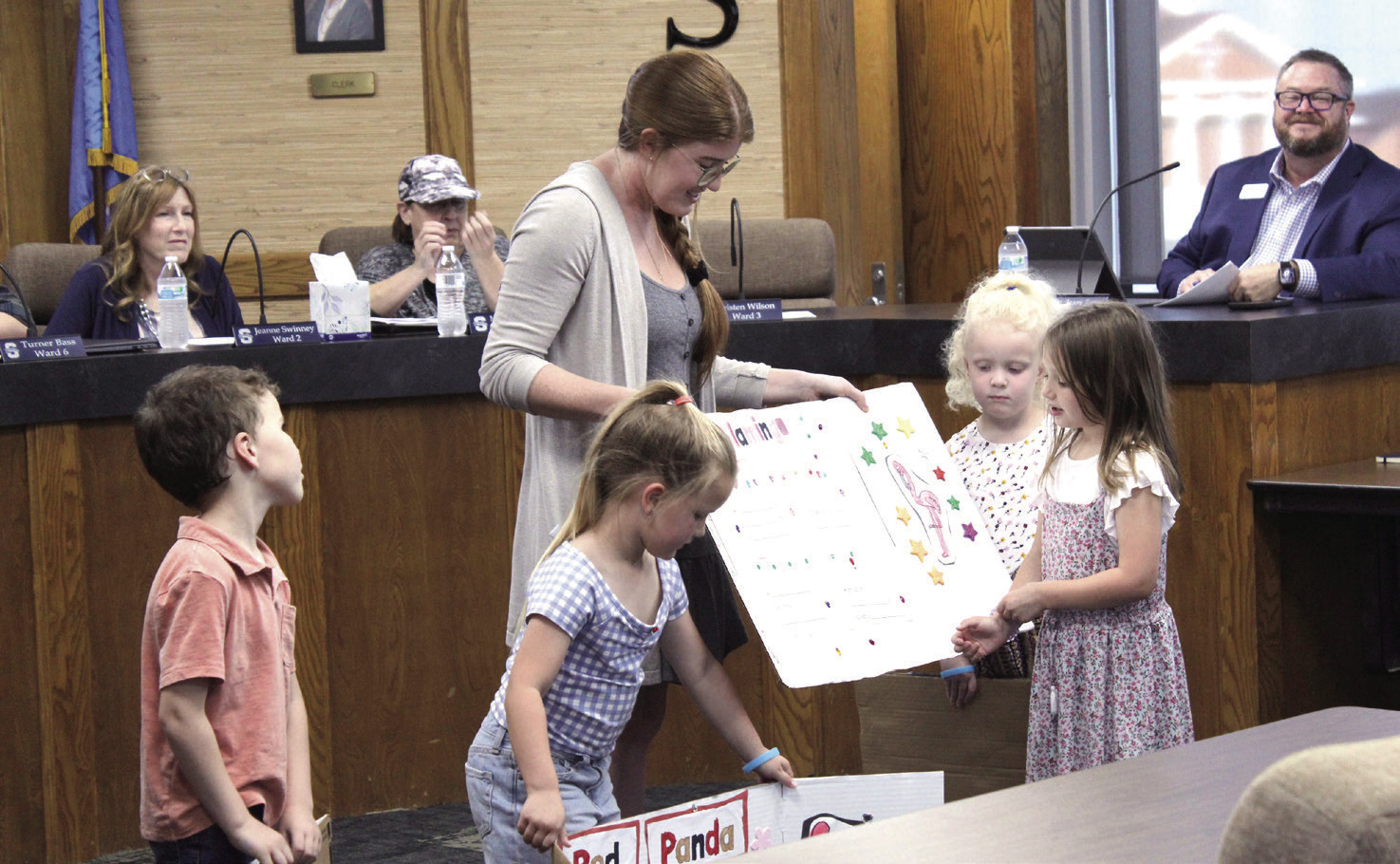 Shawnee Early Childhood Center teacher Hannah Jett holds a display board for Callie Lynch, as she speaks about flamingos during the Shawnee Board of Education meeting on April 13. Jett's class researched animals, then took their display boards to the Oklahoma City Zoo to see the actual creatures. Also shown, from left, are Jacob Chism, Hattie Grimes and Clara Gragg. In the background, board members Jeanne Swinney and Mandy Hillhouse and Superintendent Dr. Jason James listen.