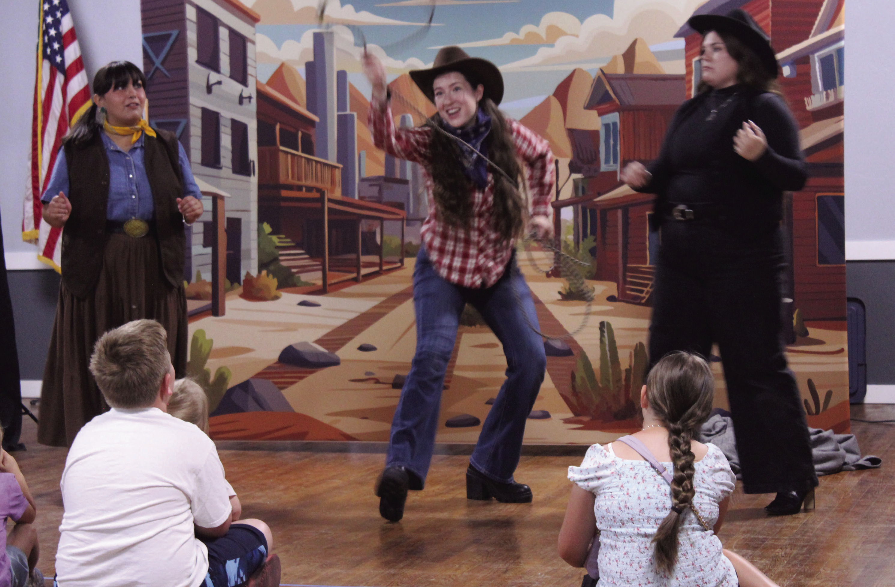 "Pop Magano," played by Savannah Gordon, demonstrates her skill with a lasso, as "Tam," played by Olivia Flores, left, and the "Queen of Knocked Sara Stro," played by Cheyenne Holland, watch during "The Magic Flute Goes West!" Presented by Painted Sky Opera as a McLoud Public Library event, the kid-friendly opera was performed at McLoud's American Legion on July 17. In August, Painted Sky Opera will present Mozart's "The Magic Flute" at the Civic Center in OKC. 