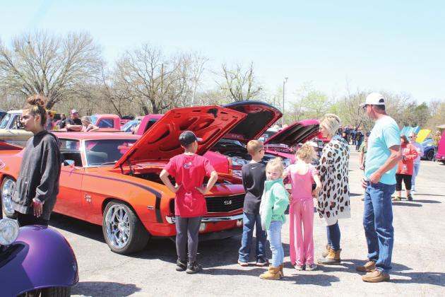 Lay Blue, far left, Dray Blue, Elijah Coughran, Annistyn Coughran, Gracie Holmes, Misti Casey, and Bobby Holmes look over the cars at the Sixth Annual Bethel Band Boosters Car Show on April 9, including a 1969 Chevy Camaro SS owned by Shane Vice.